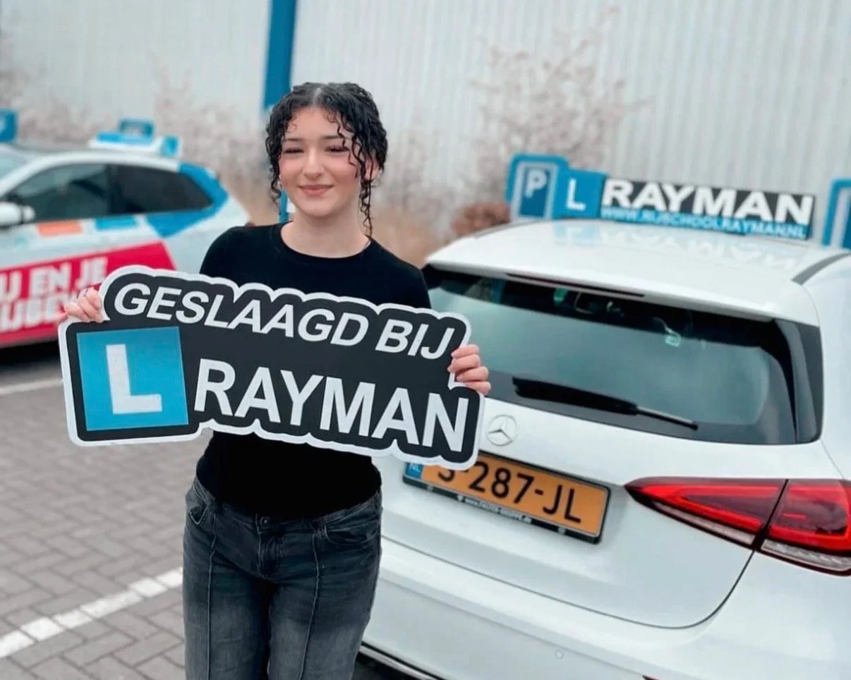 Vrouw uit Deventer met bord geslaagd bij Rijschool Rayman in haar handen, ze is geslaagd voor haar autorijbewijs