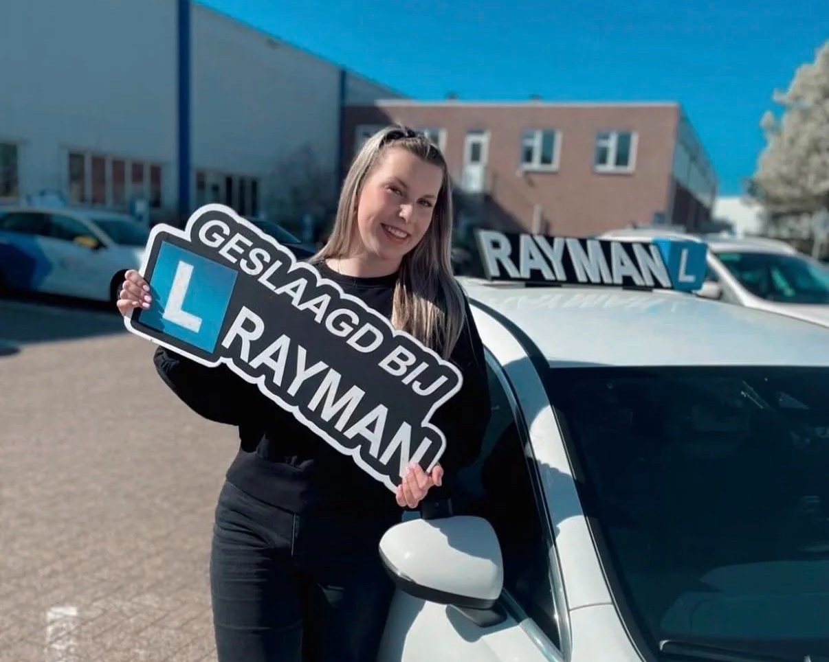 Vrouw uit Terwolde met bord geslaagd bij Rijschool Rayman in haar handen, ze is geslaagd voor haar autorijbewijs