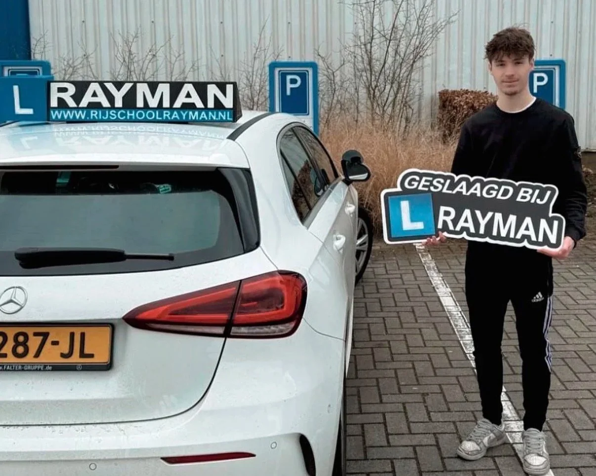 Een jongeman uit Diepenveen die geslaagd is bij Rijschool Rayman en een bord in zijn handen houdt met Geslaagd bij Rayman