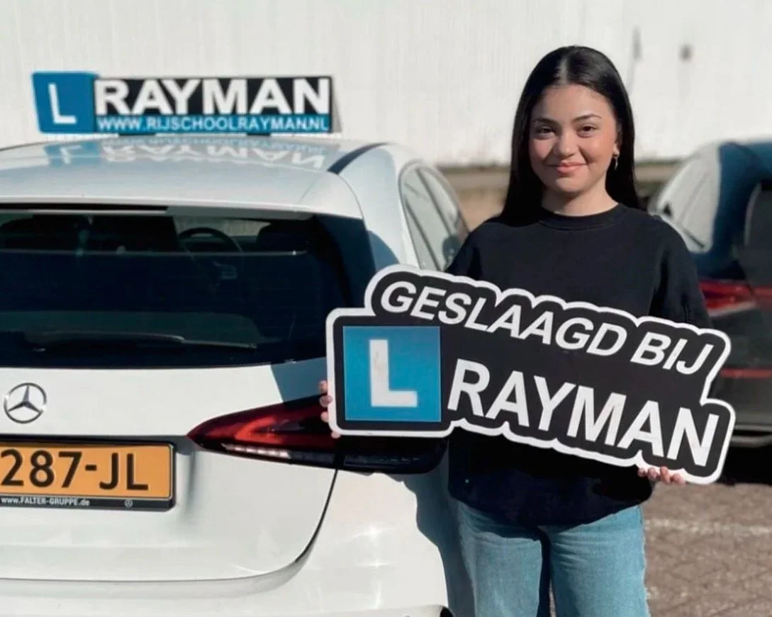 Een jongedame uit Schalkhaar die geslaagd is bij Rijschool Rayman en een bord in zijn handen houdt met Geslaagd bij Rayman