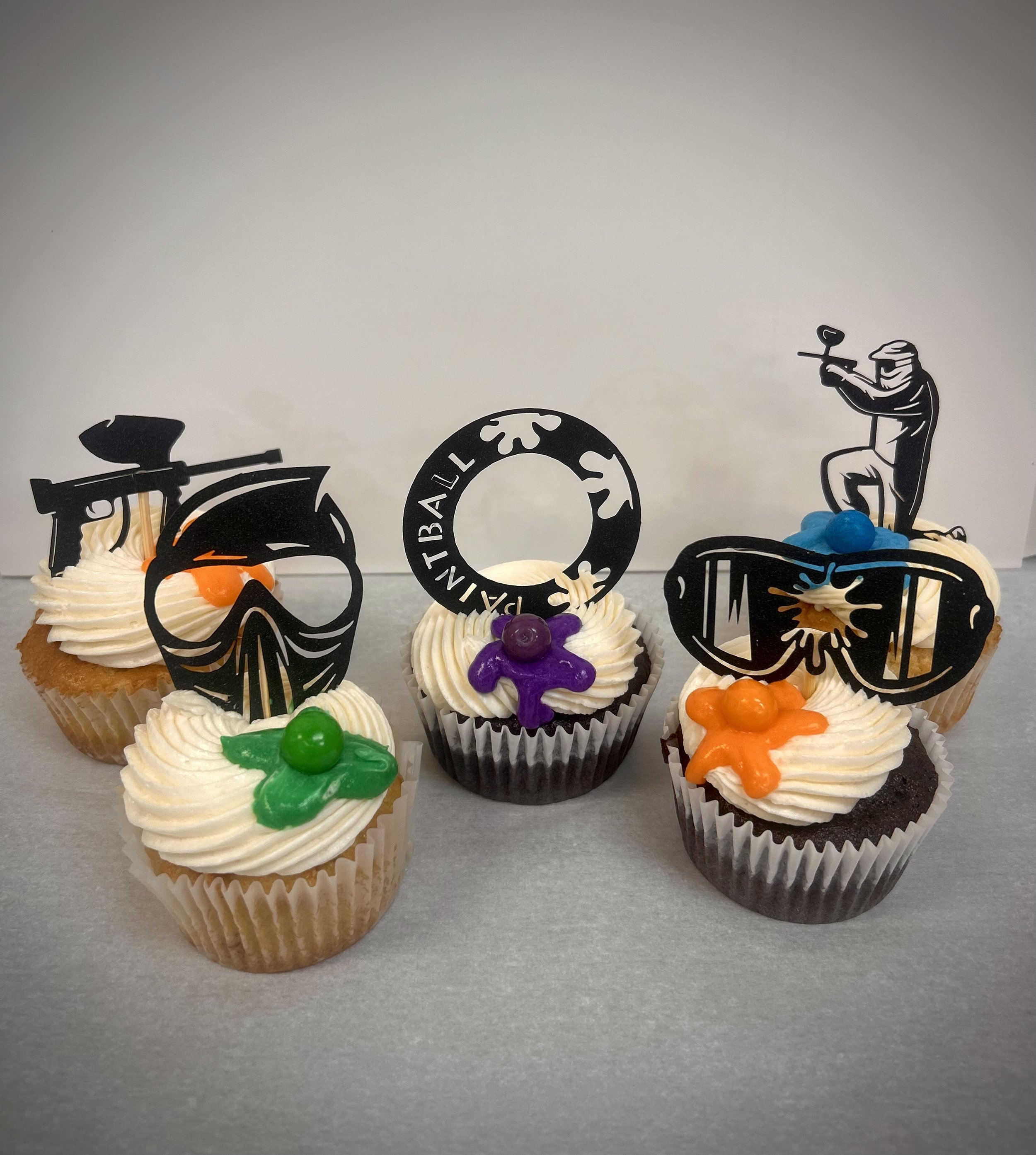 Cupcakes with tropical themed toppers, including sunglasses, scuba diver, and snorkeler, decorated with colored icing and small candy accents.