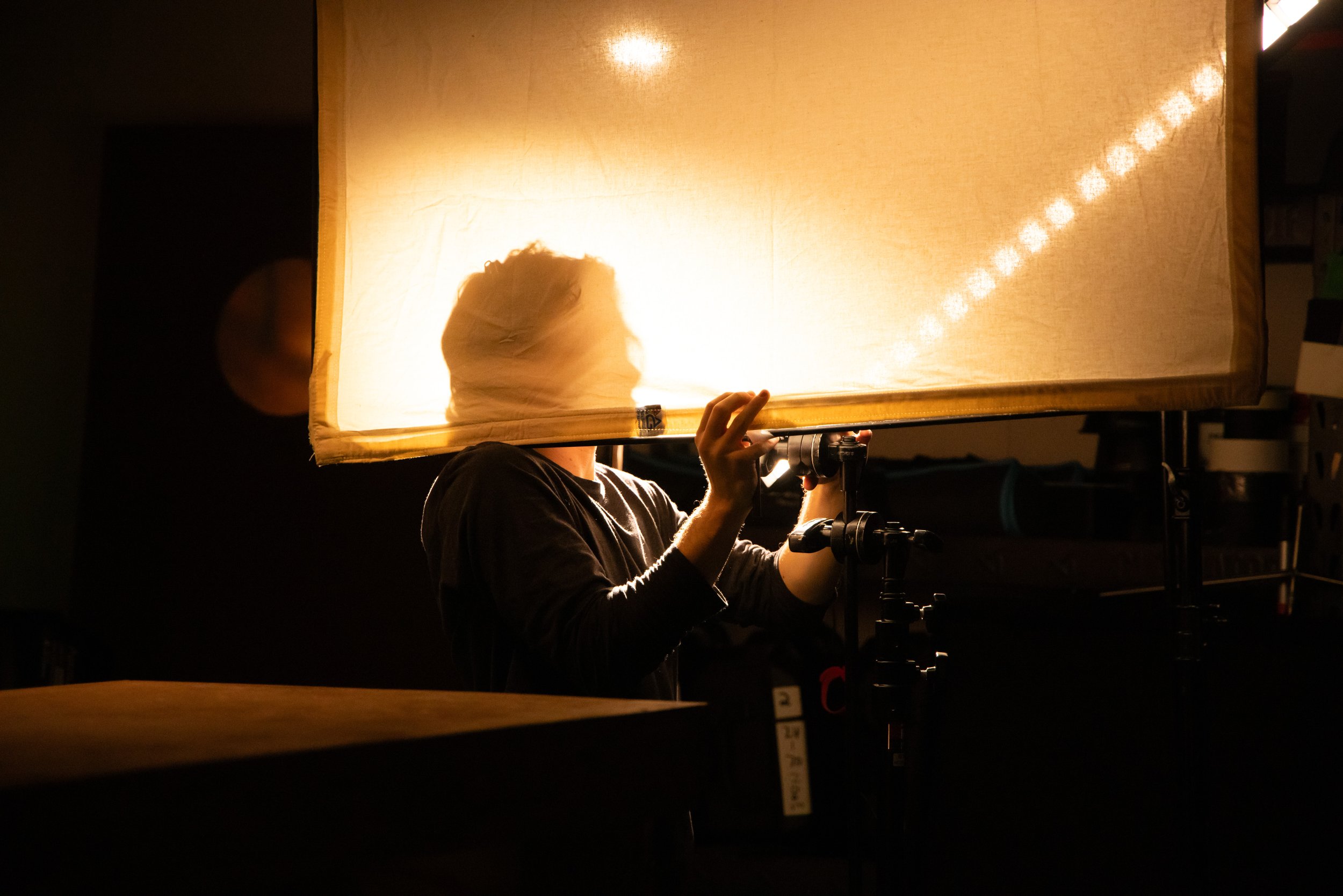 A person adjusting a large, illuminated softbox light in a photography studio.
