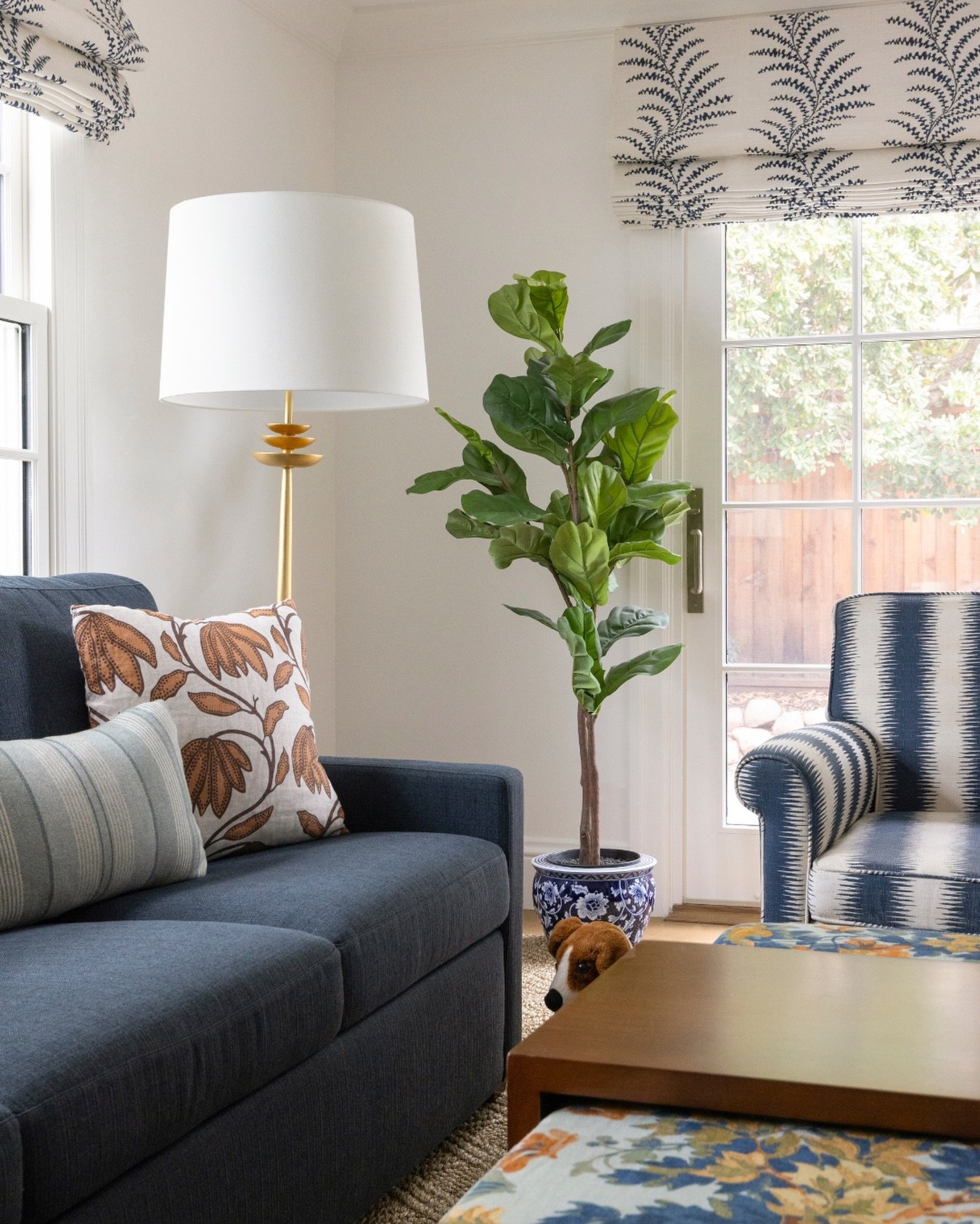 A tailored roman shade, a classic blue sofa, patterned upholstery, warm wood tones, and a touch of greenery, all working together to create a space that feels collected, comfortable, and inviting.

It&rsquo;s never just one piece that makes a room. I