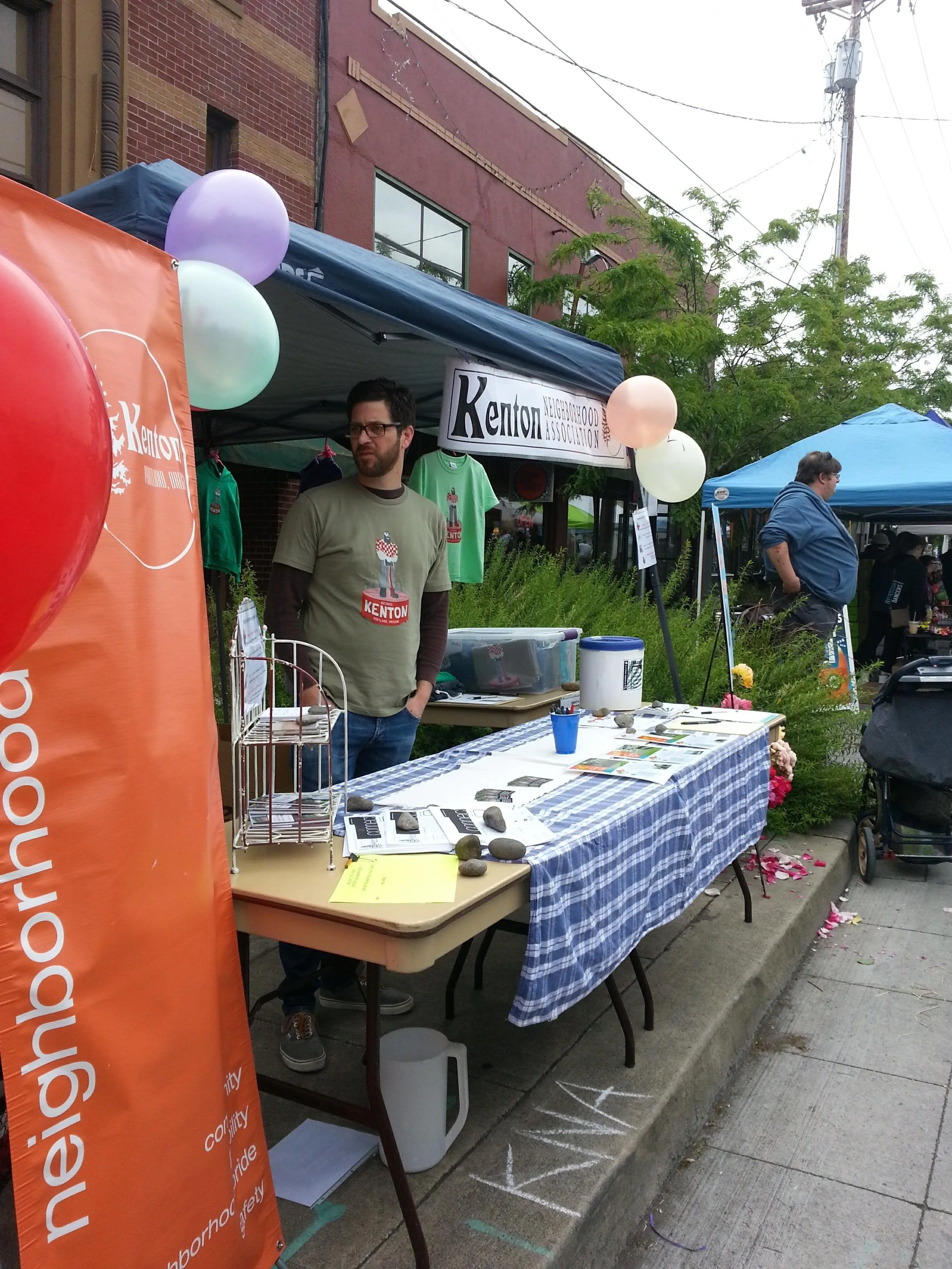 A man staffs the Kenton Neighborhood Association booth at a community event.