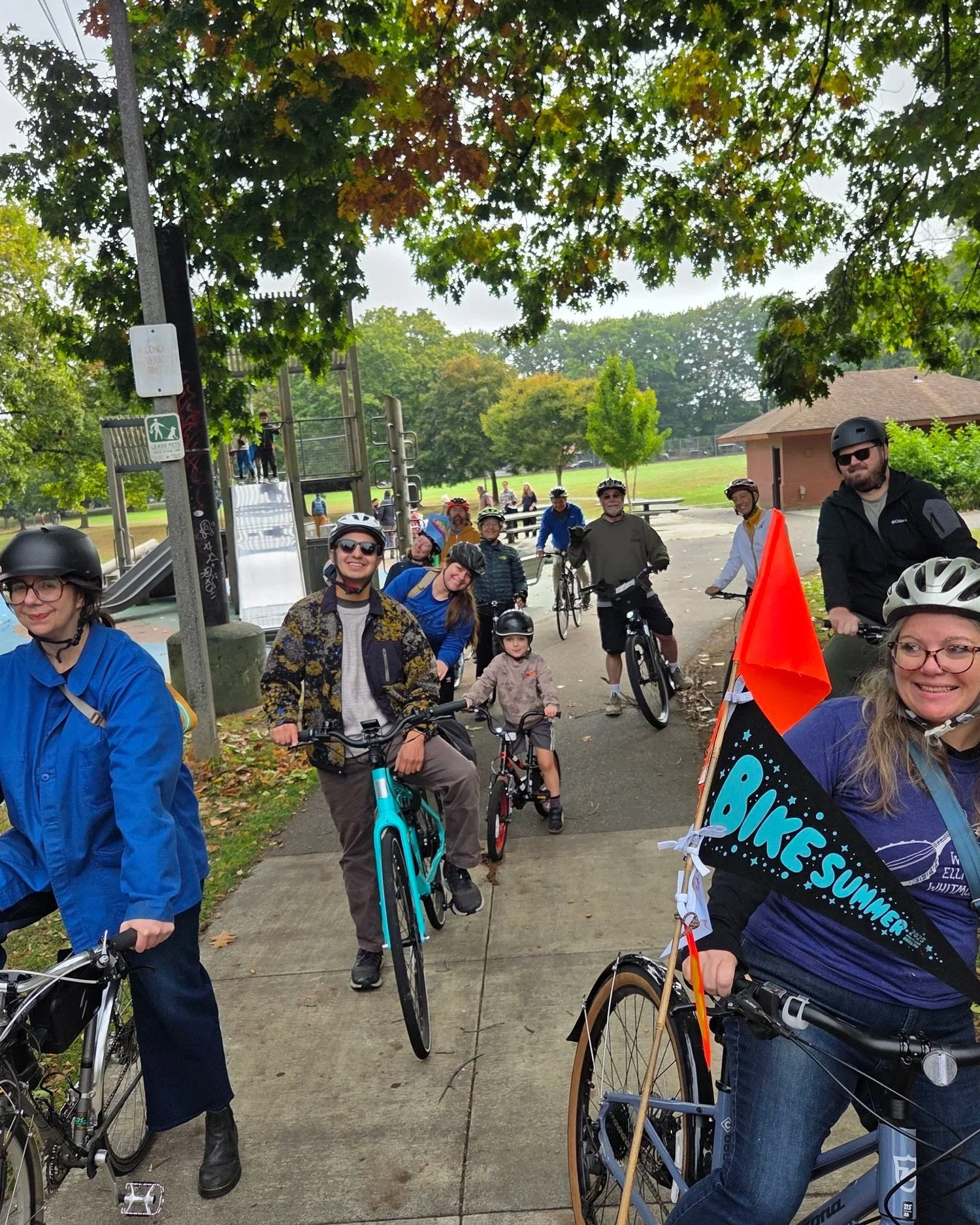 A long line of bike riders smile while kicking off a bike ride.