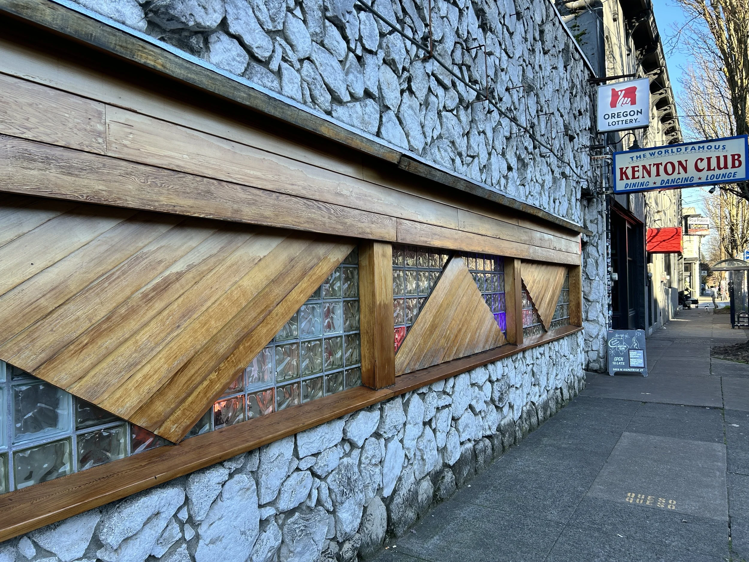 Kenton Club exterior; the large, white stone mosaic facade is bisected horizontally by a long glass and wooden window.