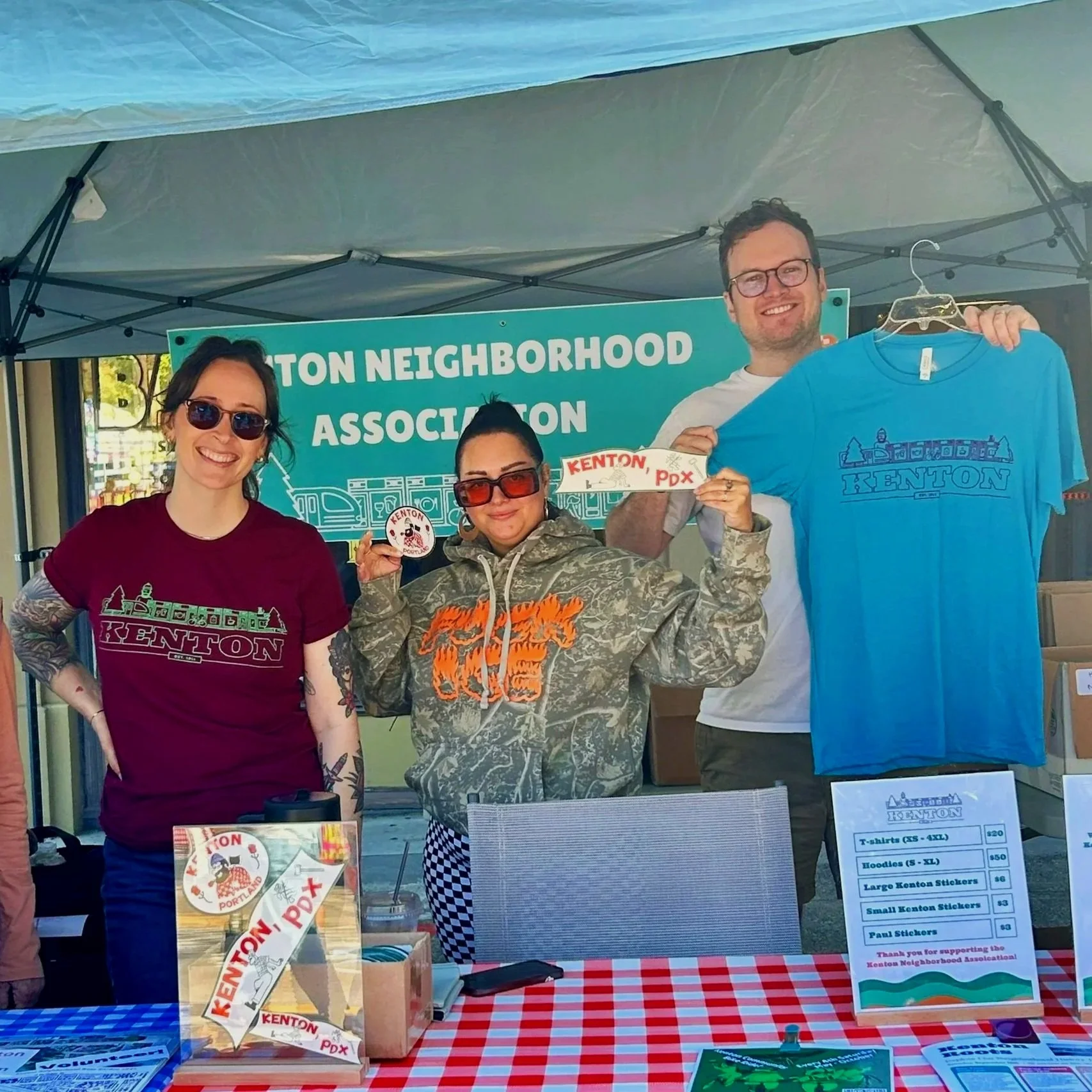 People modeling and holding up Kenton tees and stickers.