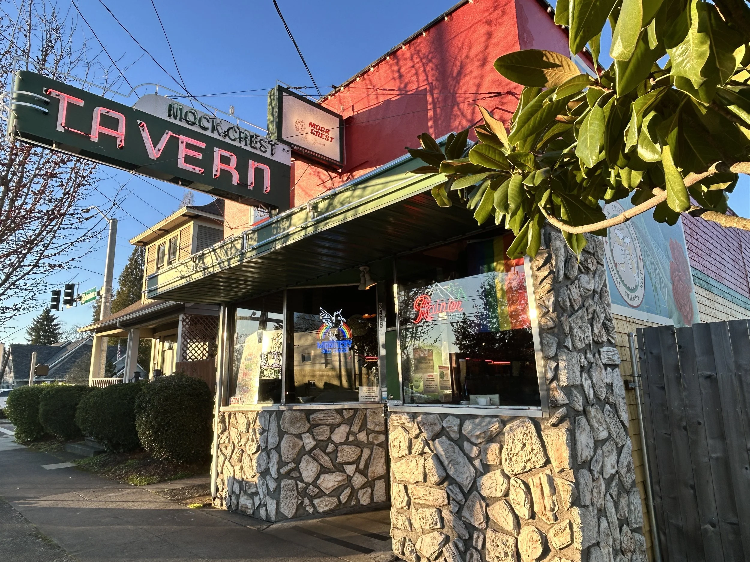 Mock Crest Tavern exterior; the historic neon sign glows brightly against the blue sky.