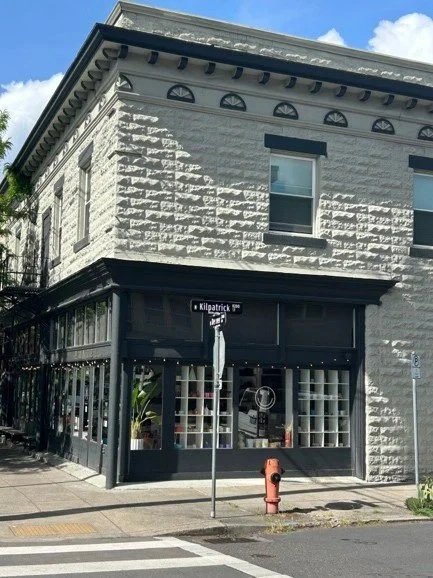 Commercial building with a first floor facade of windows and wood painted black, and a second floor facade of rusticated blocks painted cream.