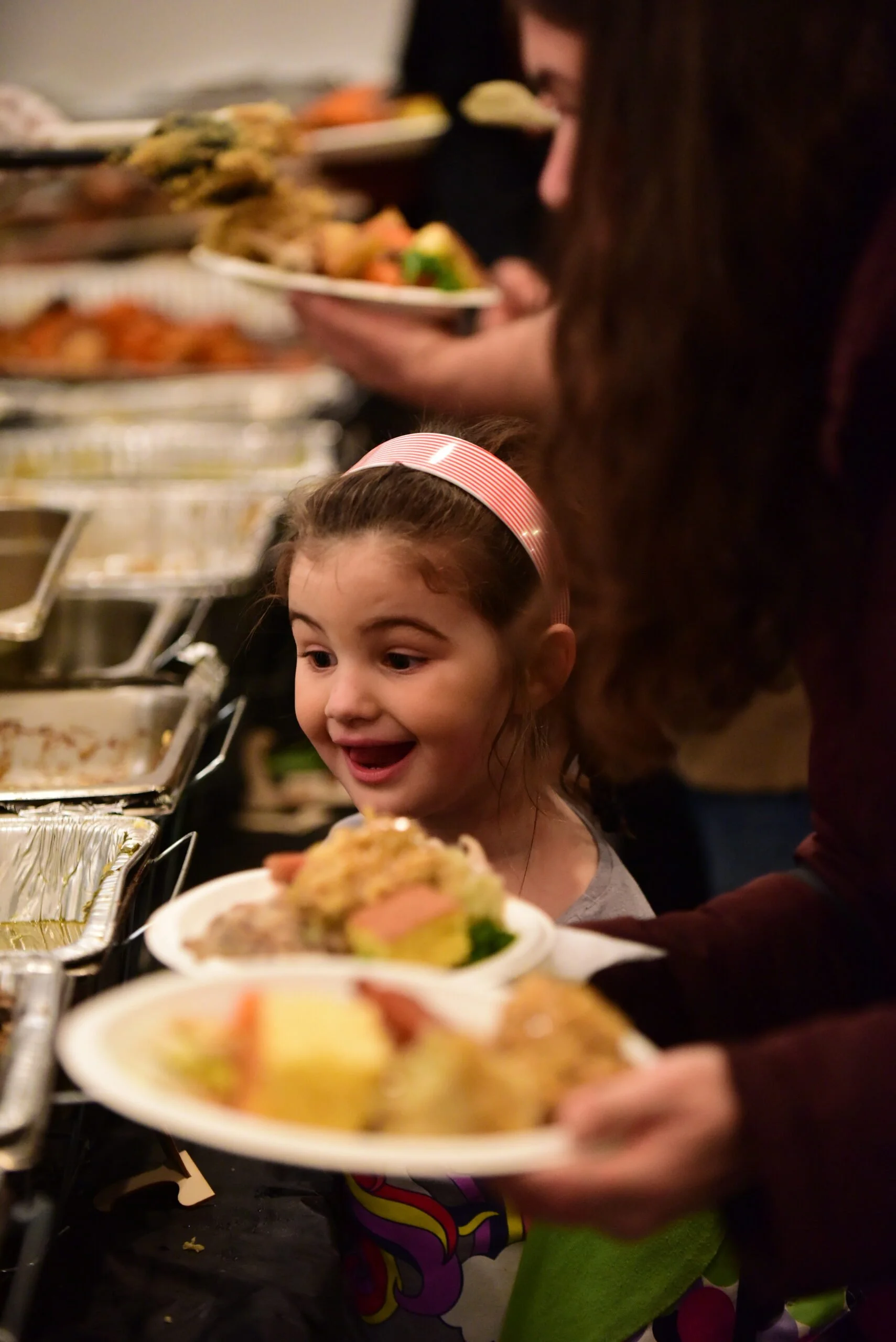 A young girl smiles while making a plate from a Thanksgiving buffet