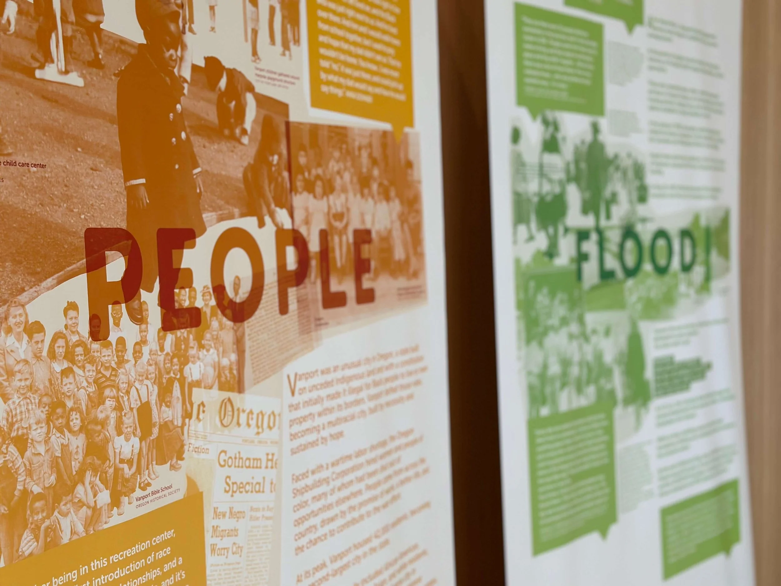 Two exhibition panels; the one on the left features images and text in shades of orange with large text reading "PEOPLE" and the one on the right features images and text in shades of green with large text reading "FLOOD"