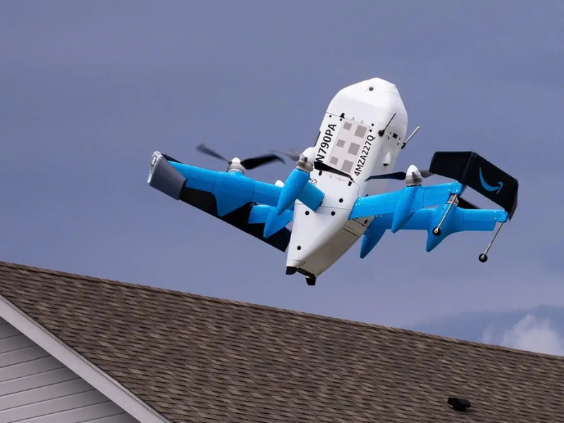 Commercial delivery drone hovering over a house rooftop.
