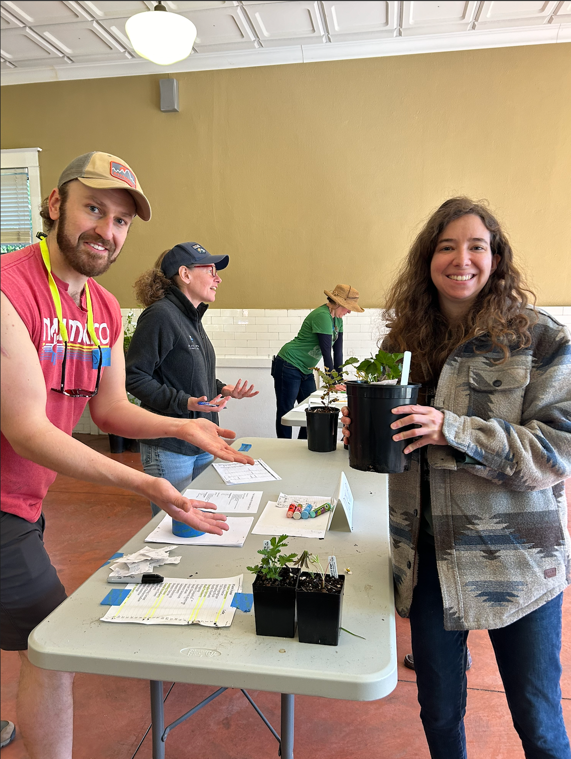 A man hands a potted plant to a woman.