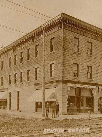 Sepia tone historic photo of the Kenton Hotel; three men stand on the corner and the roads are unpaved.