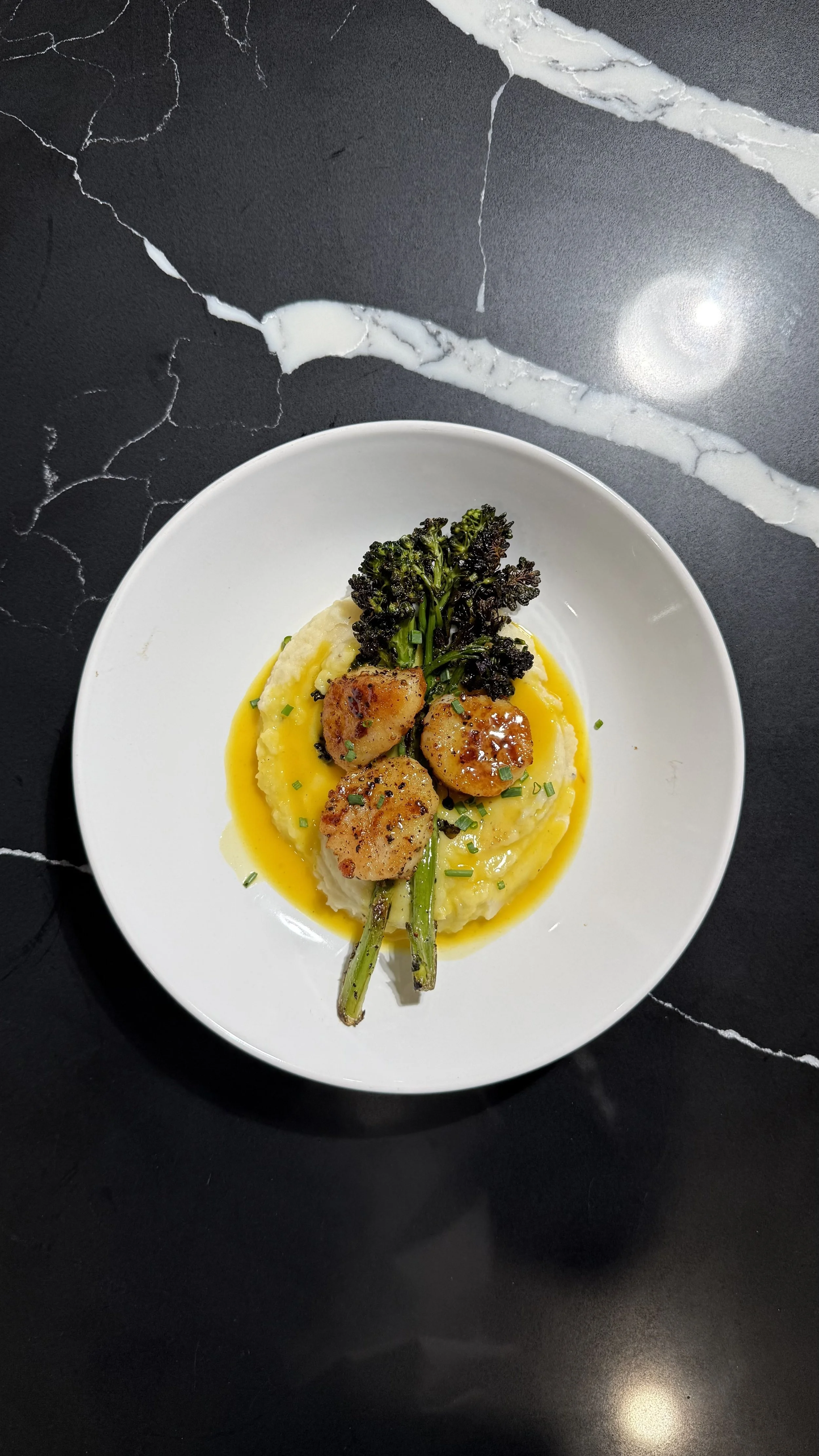 Golden pan-seared scallops served with creamy mashed potatoes, broccolini, and saffron beurre blanc.