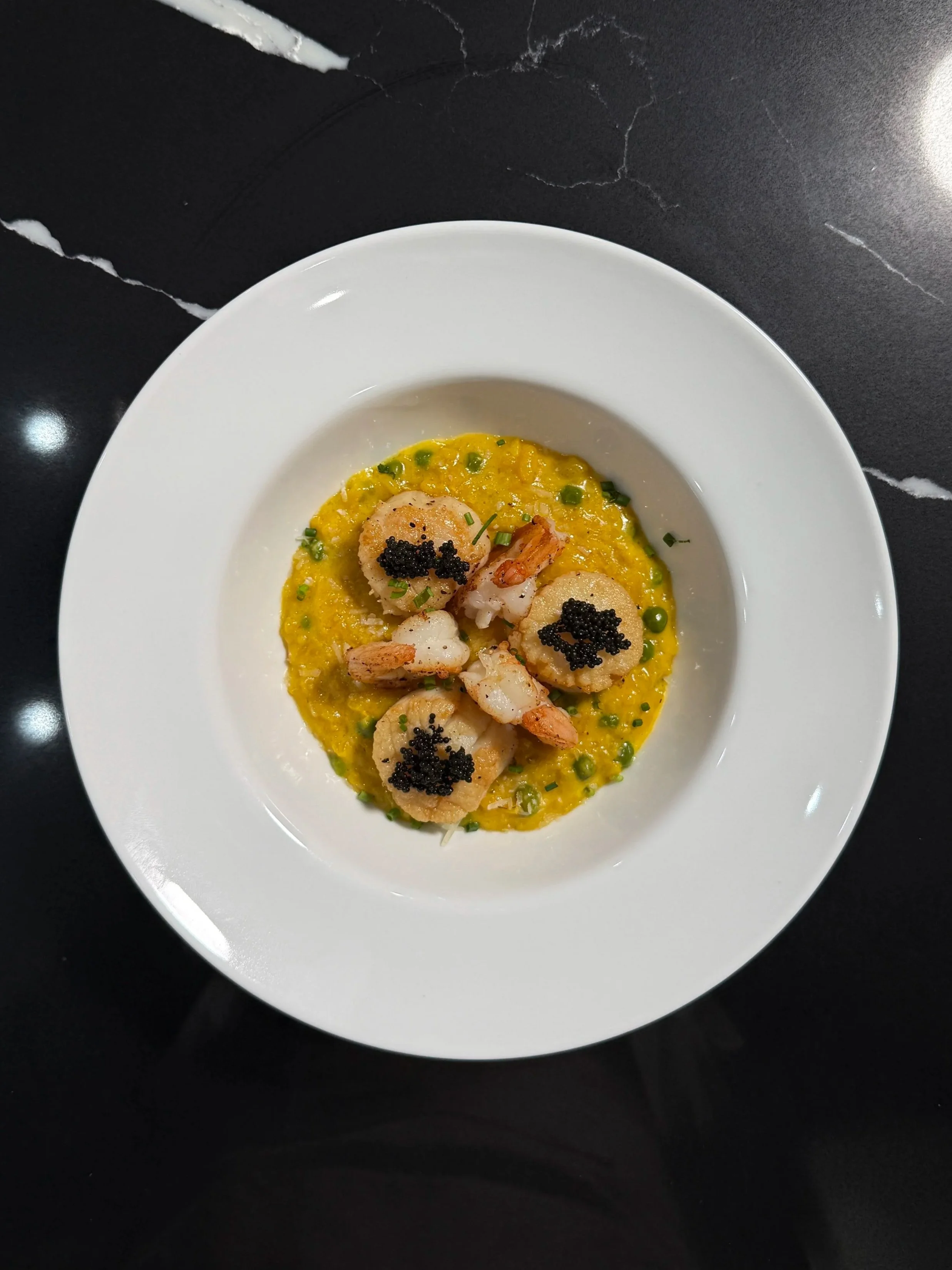 Saffron seafood risotto topped with seared scallops, shrimp, sweet peas and caviar.