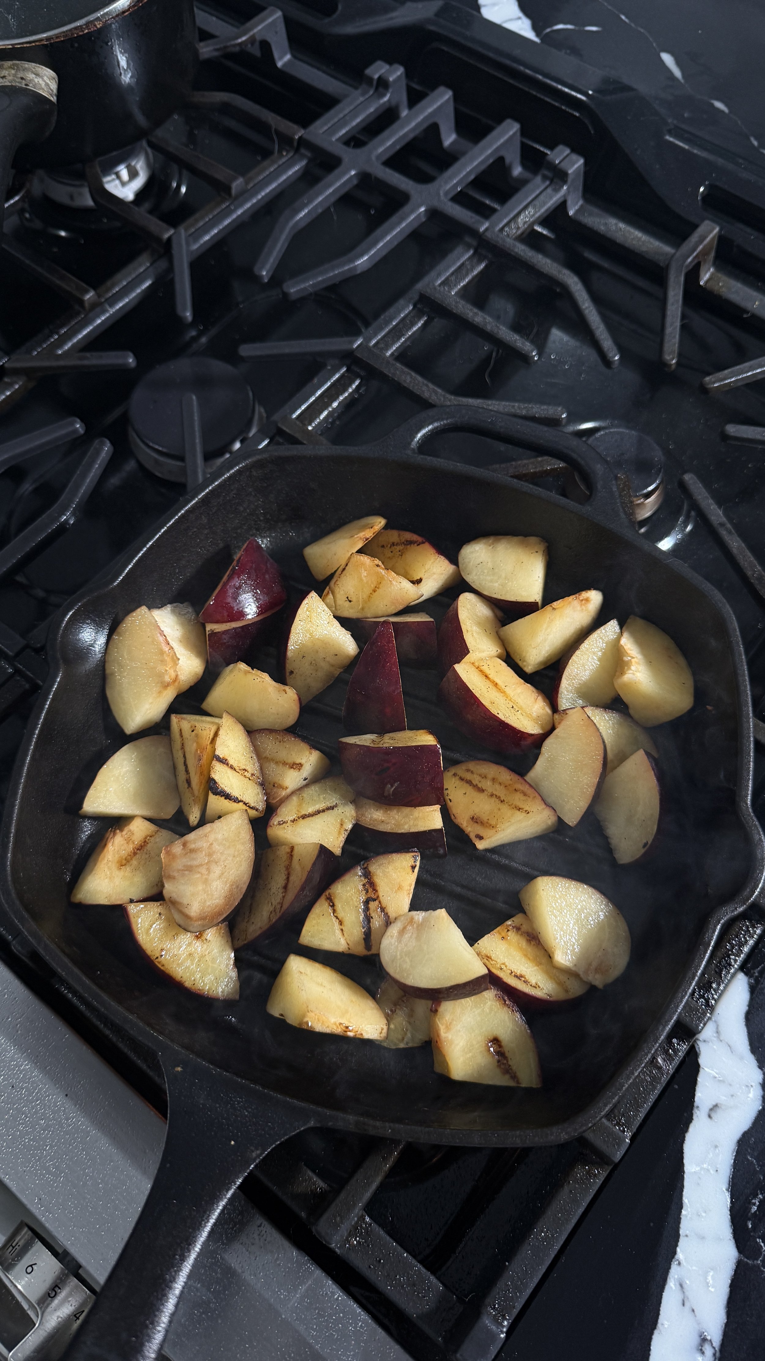 Plums searing in a cast iron pan with light caramelization