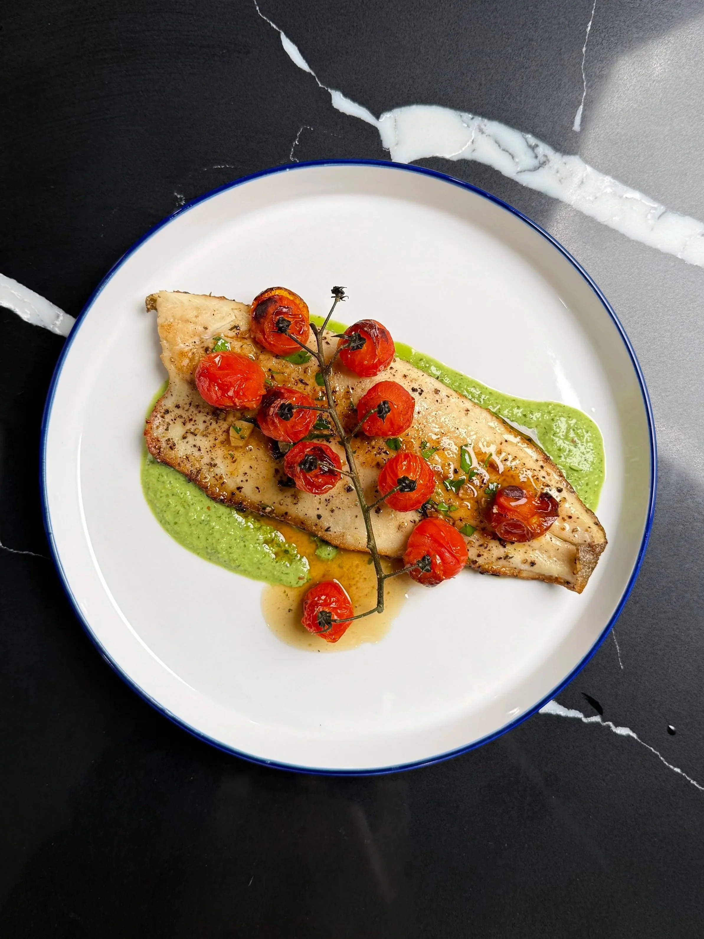 Pan-seared trout with green herb purée and roasted tomatoes, plated as an example of creative, intentional cooking.