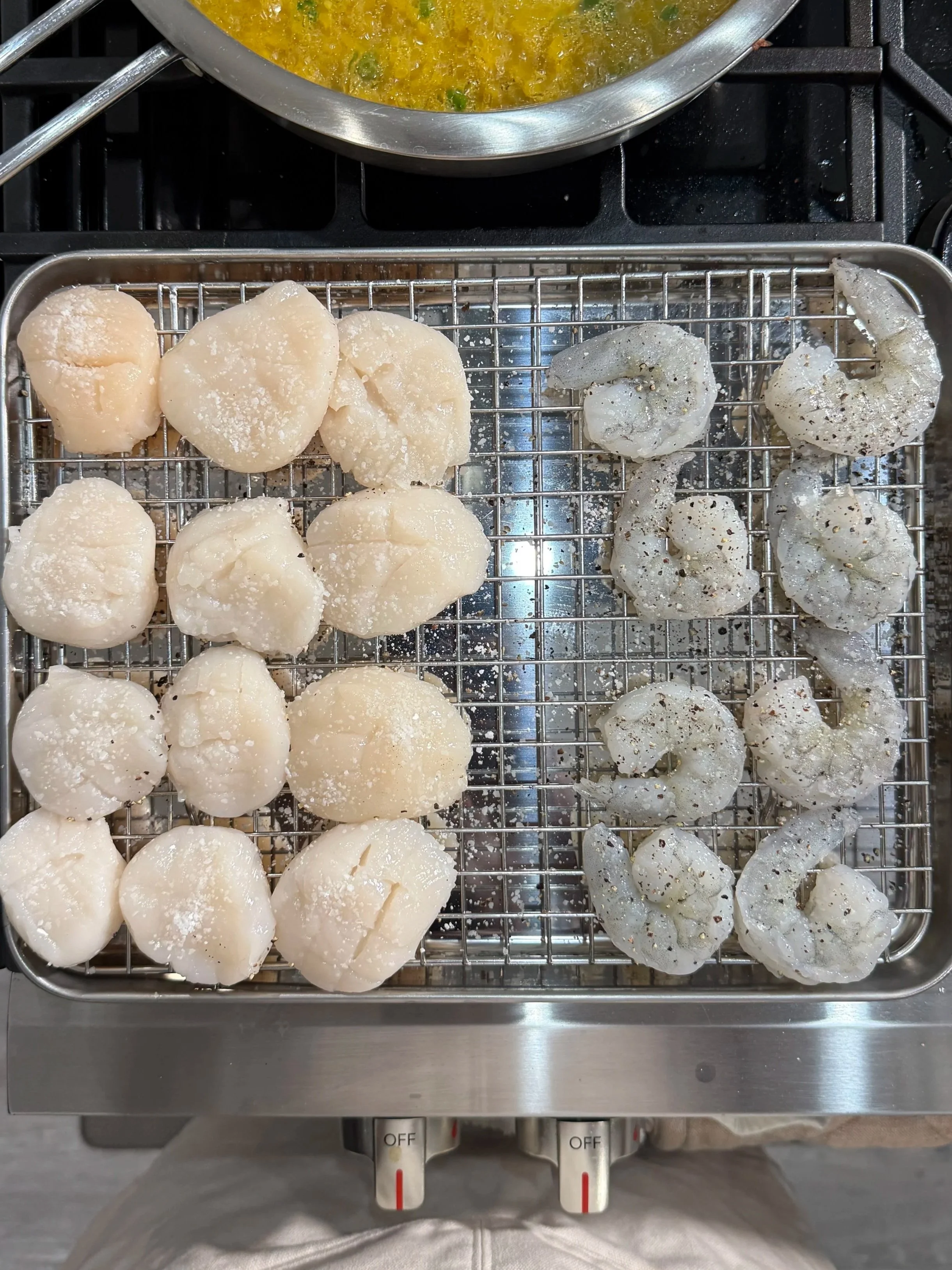 Sea scallops and shrimp seasoned and prepared for searing alongside saffron risotto.