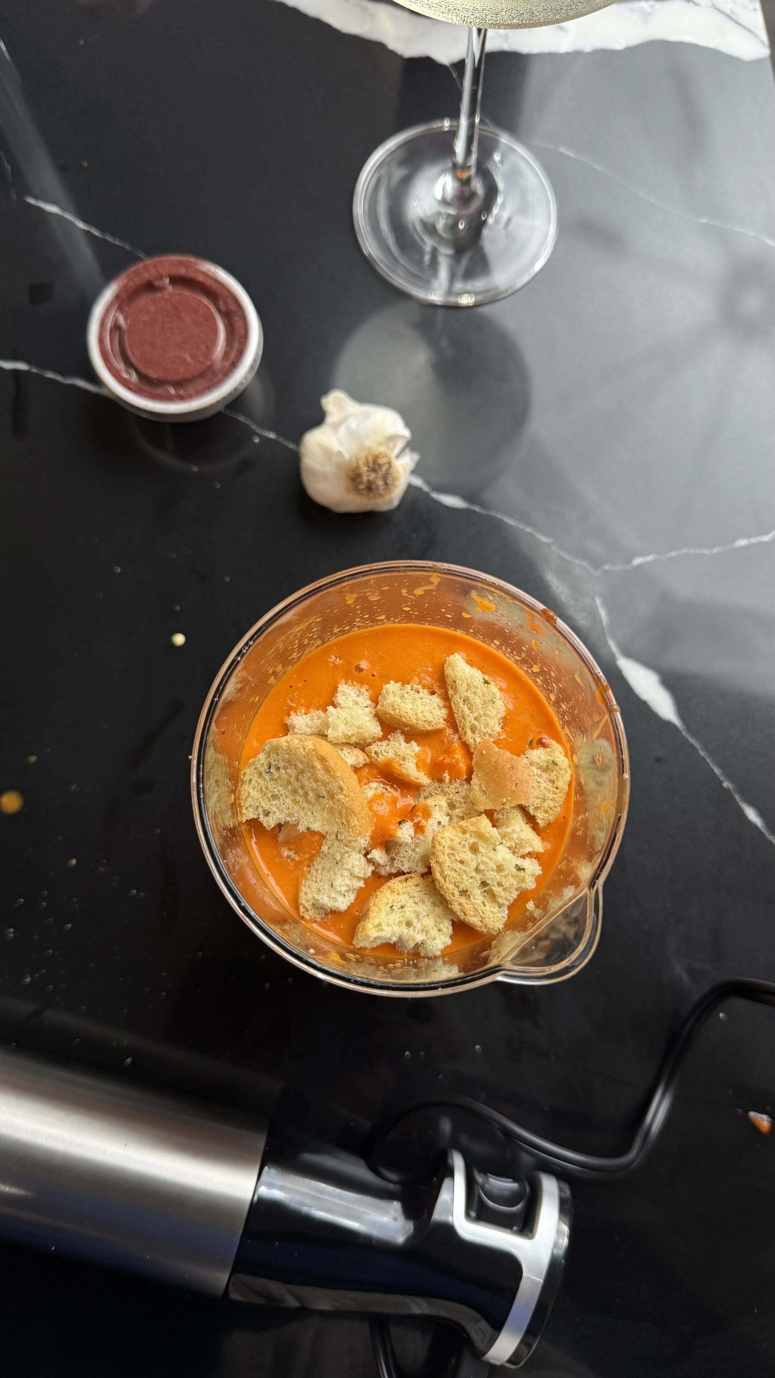 Mojo rojo sauce base with roasted peppers and toasted bread pieces inside a blender cup before emulsifying.