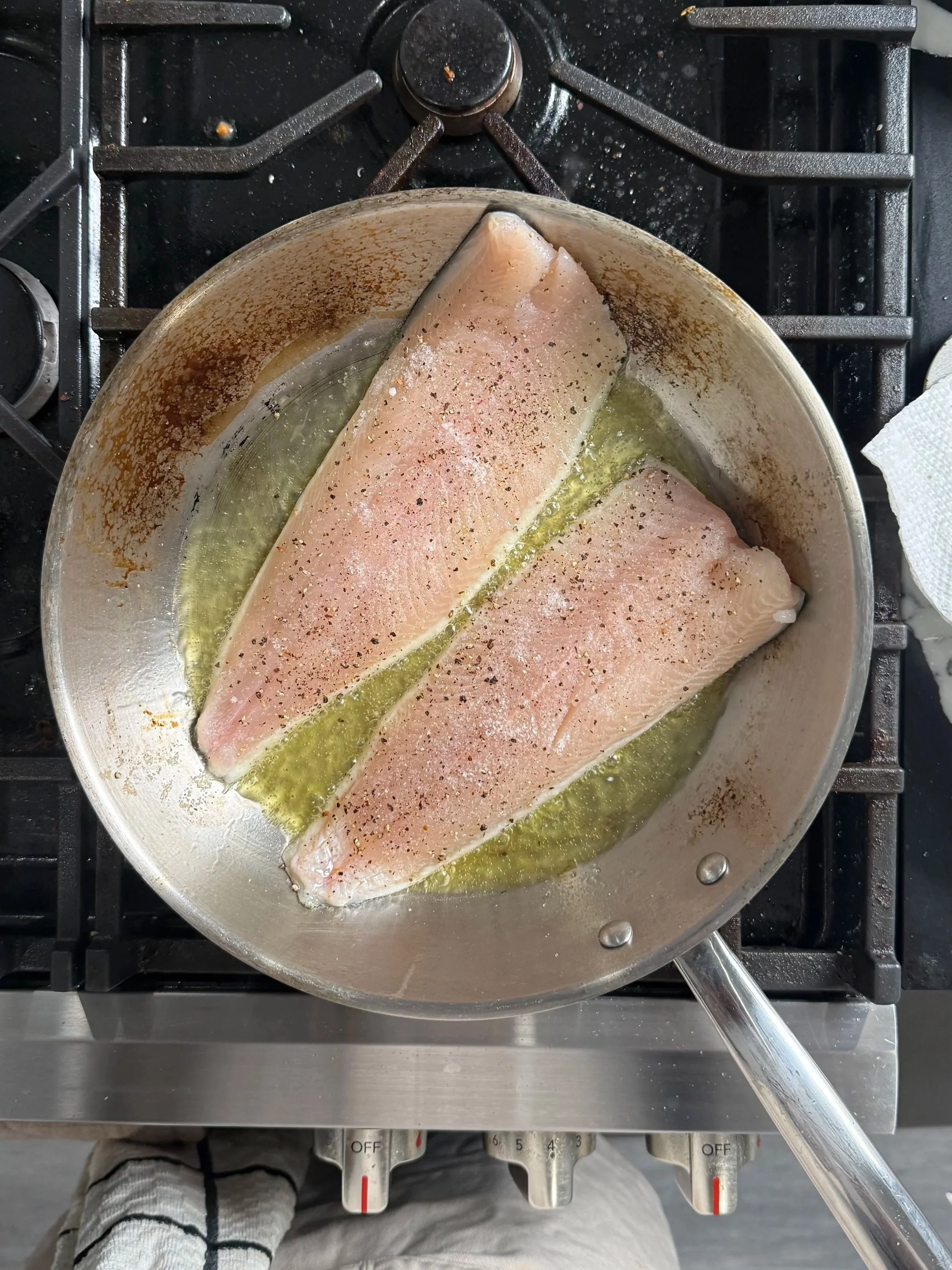 Trout fillets searing skin-side down in a hot skillet to create crispy skin