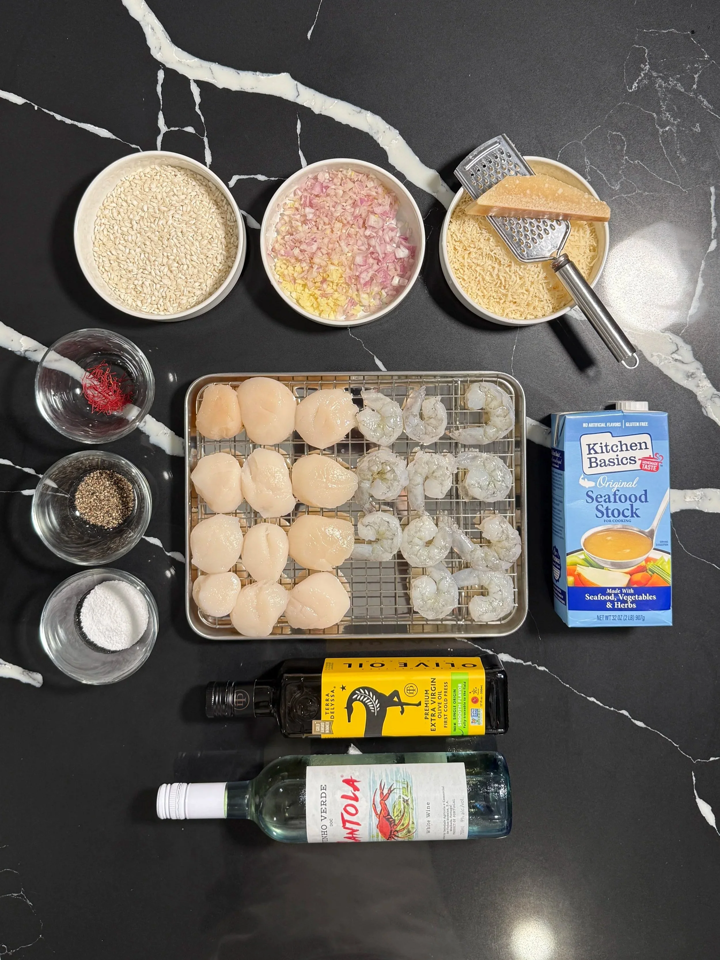 Ingredients for saffron seafood risotto including scallops, shrimp, Arborio rice, saffron, Parmesan and seafood stock.
