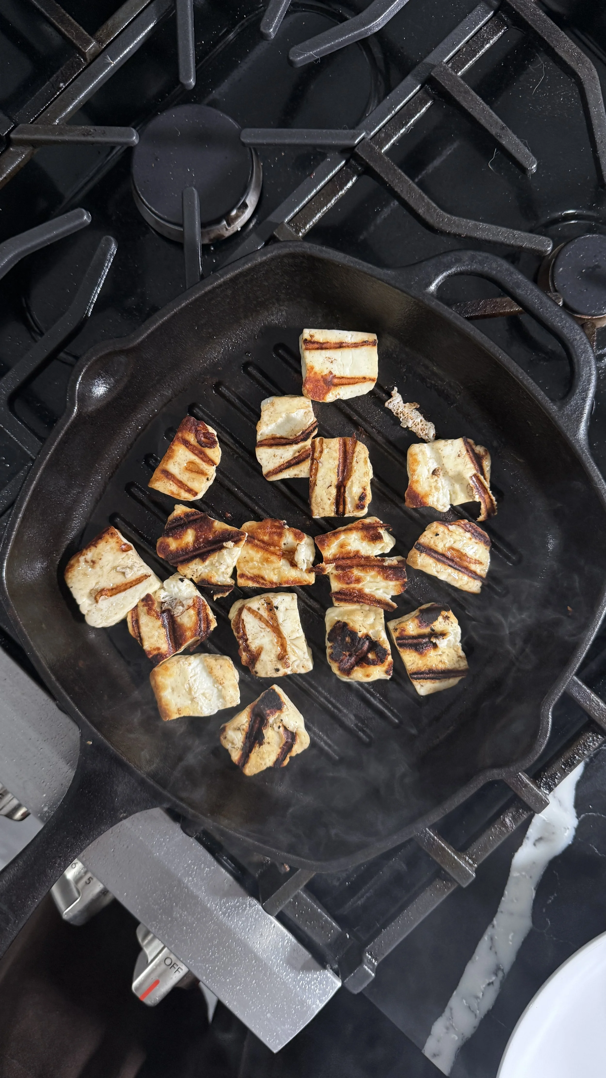 Halloumi cheese seared in a pan with golden grill marks