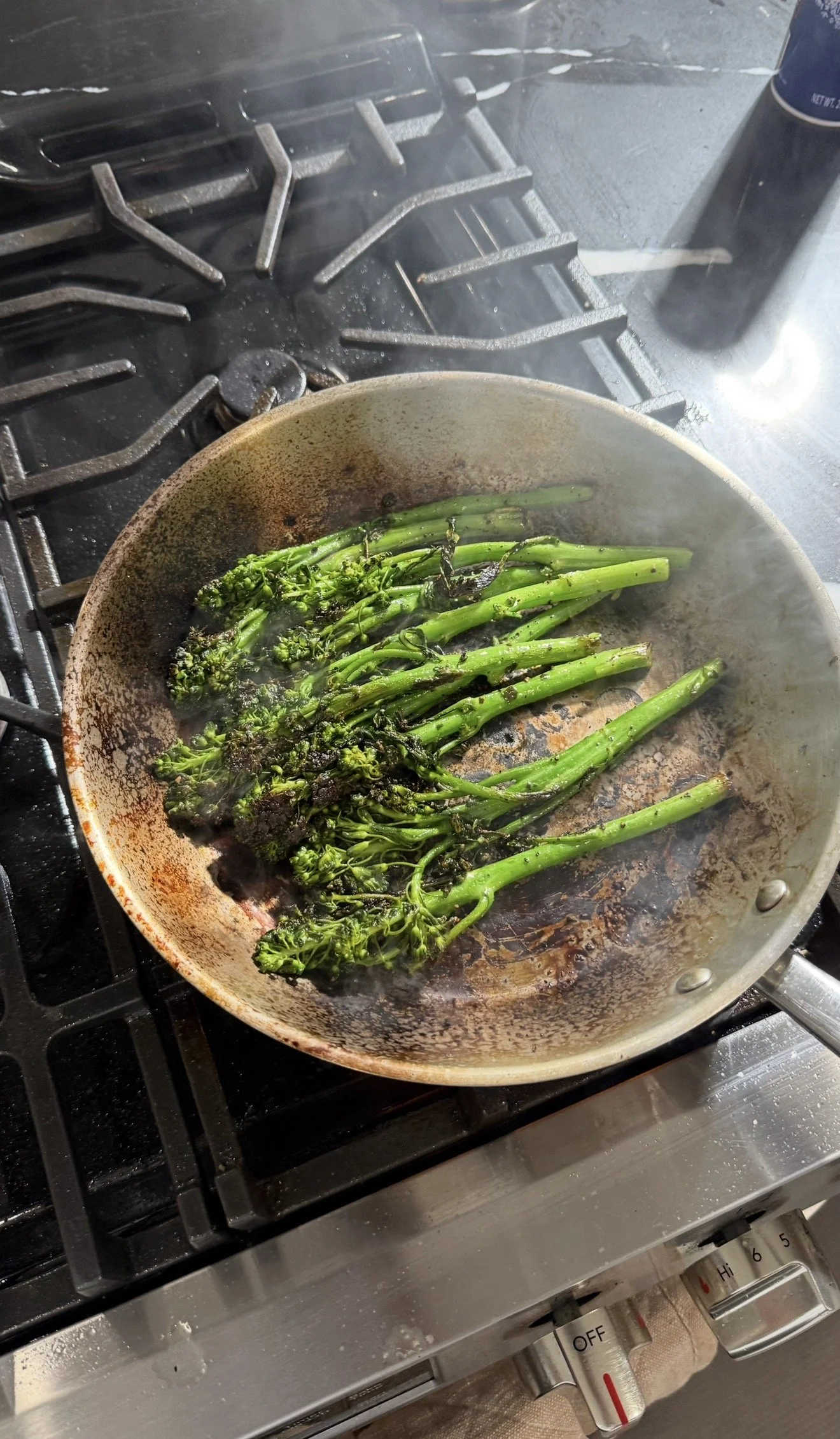Fresh broccolini sautéing in a skillet on the stovetop until tender and lightly blistered.