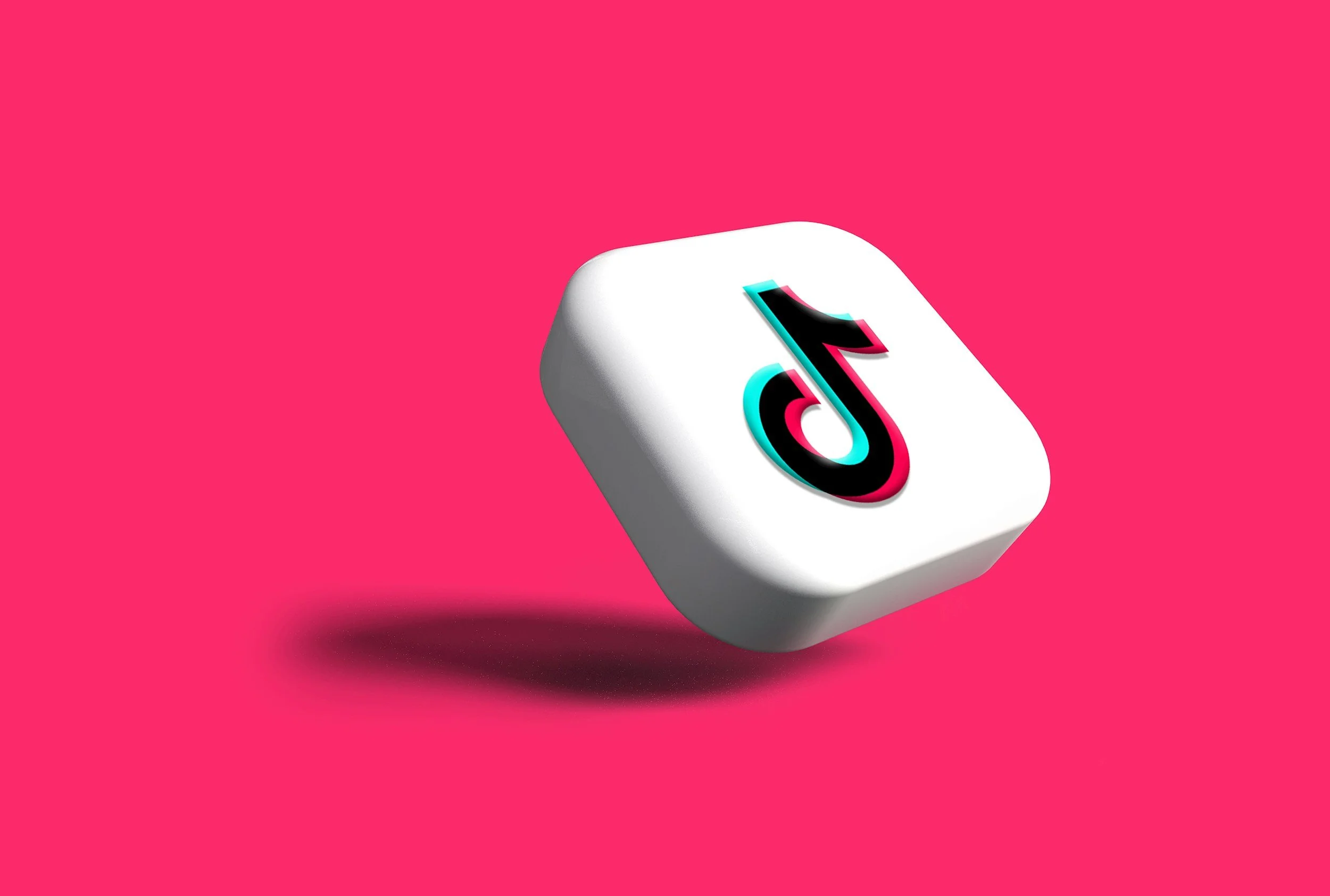 A white cube with the TikTok logo floating above a pink background