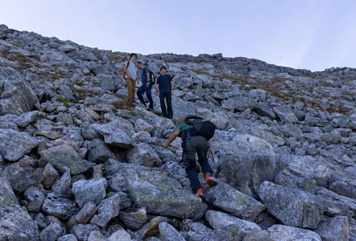 Group of hikers climbing a rocky slope on a mountain during daytime.