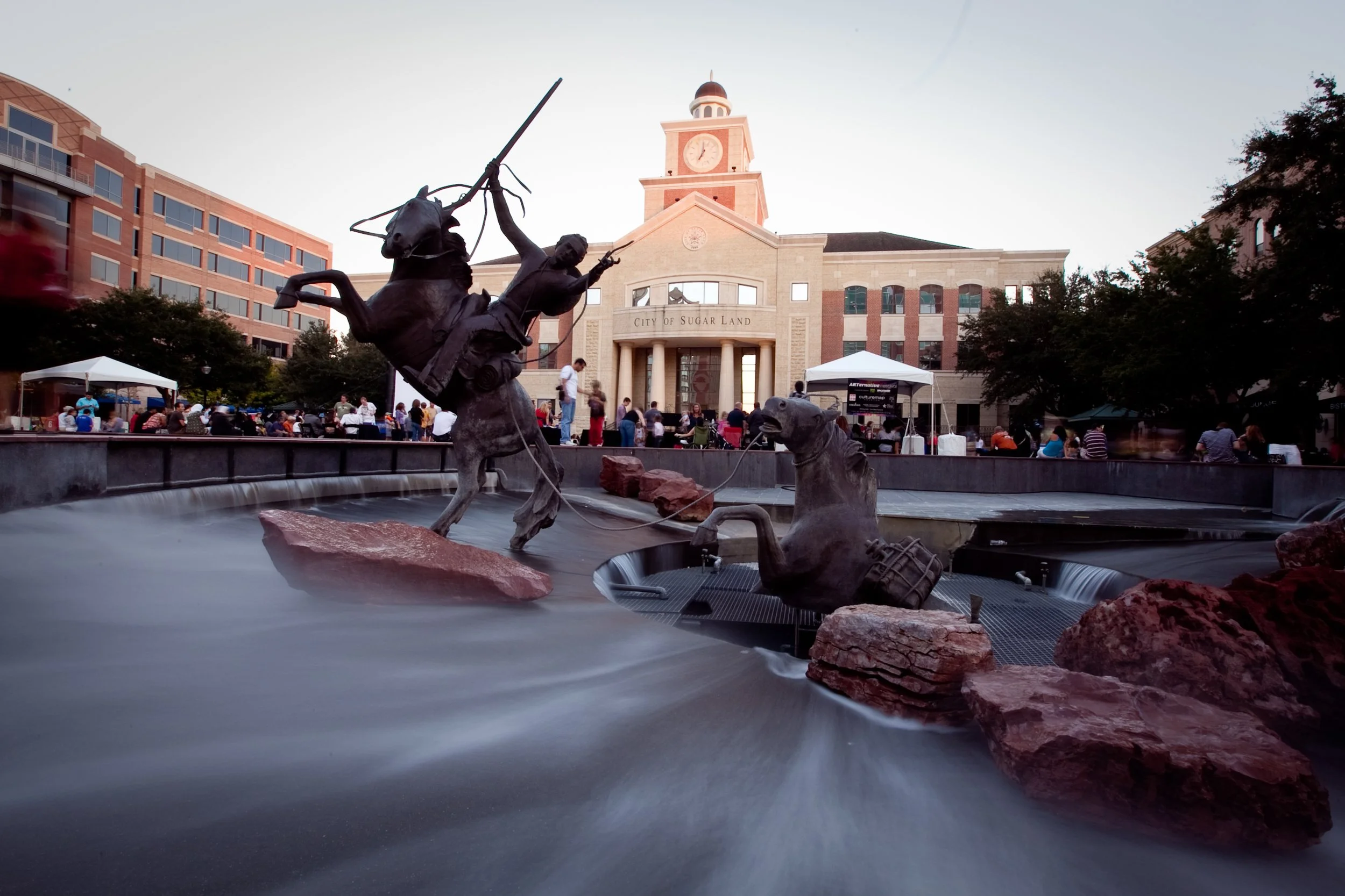 Statue fountain featuring cowboys and cows in Sugar Land, Texas, in front of City of Sugar Land building.