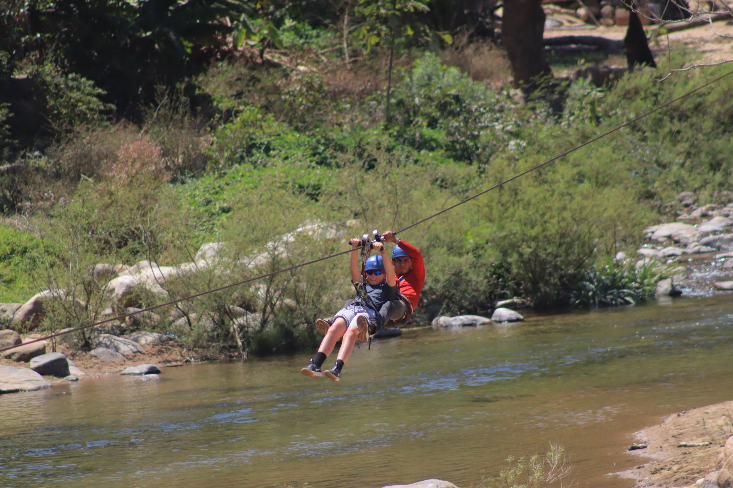 Ben and instructor ziplining over the river