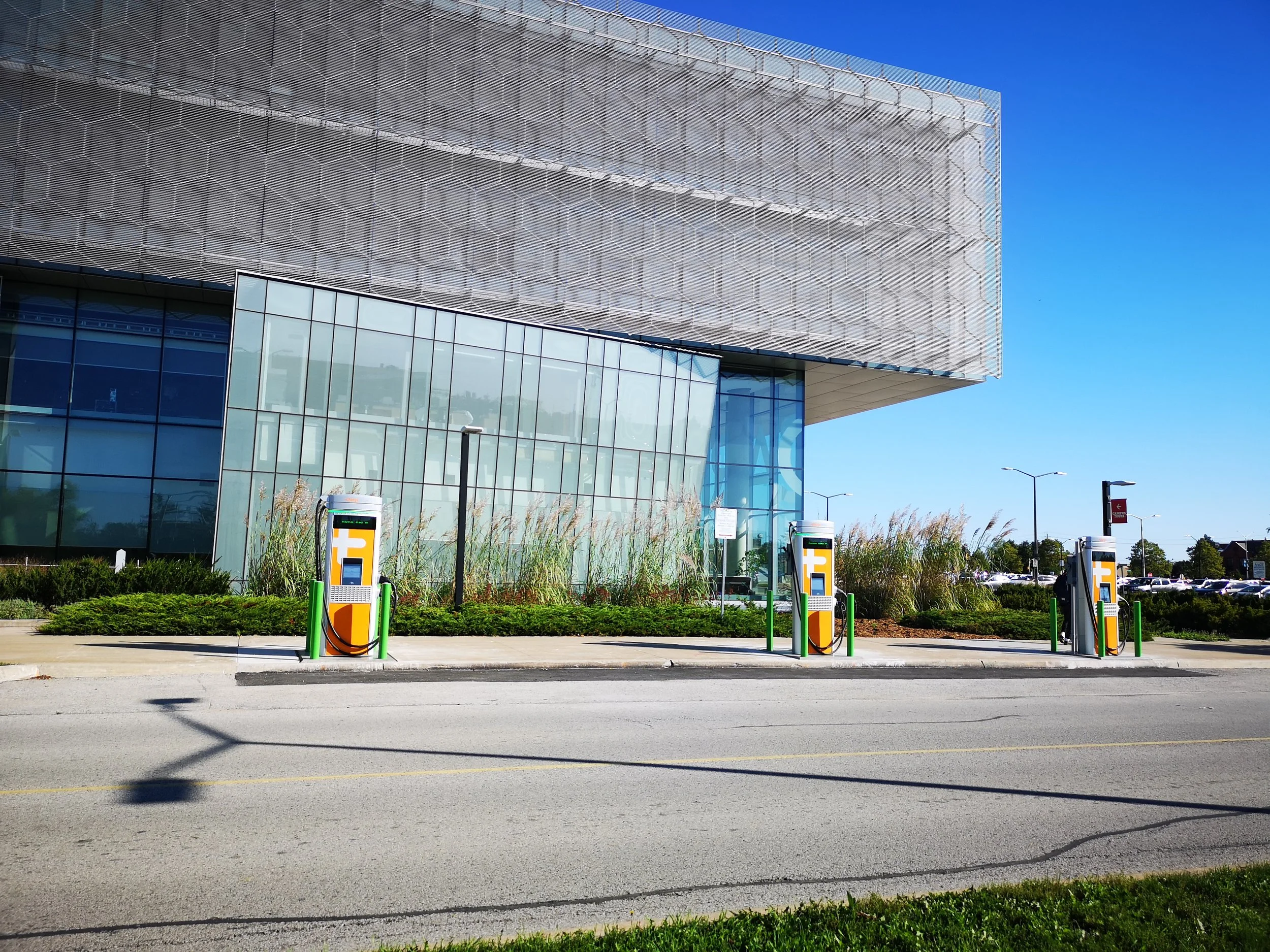 A mountain landscape featuring snow-capped peaks in the distance and a modern house on rolling green hills in the foreground.