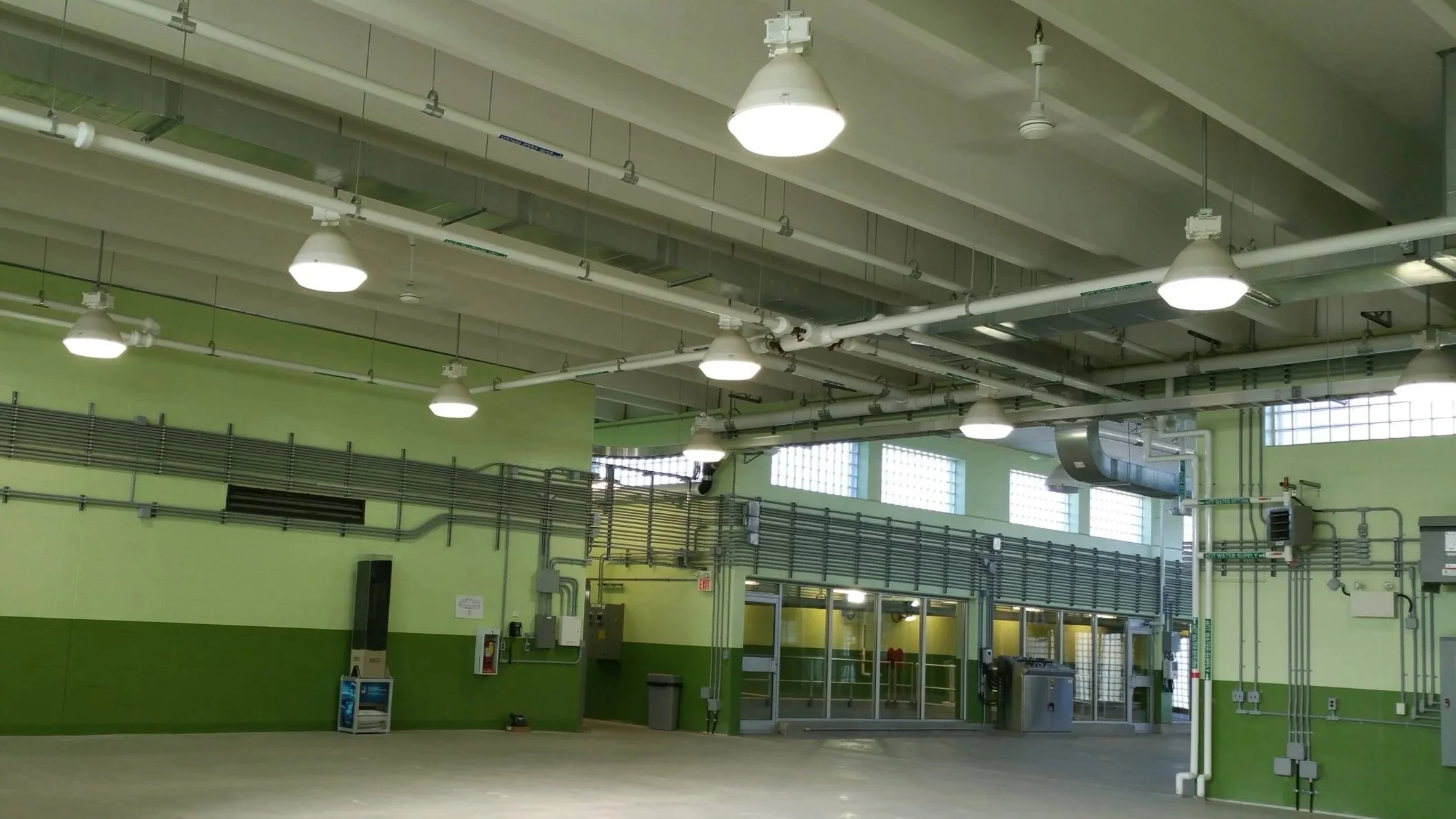 Scenic view of a turquoise lake surrounded by rolling hills and tall mountains under a cloudy sky.