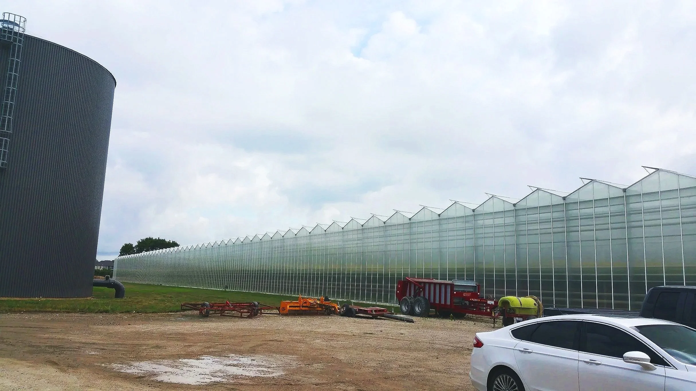 Scenic view of a lake surrounded by rolling hills and mountains under cloudy sky.