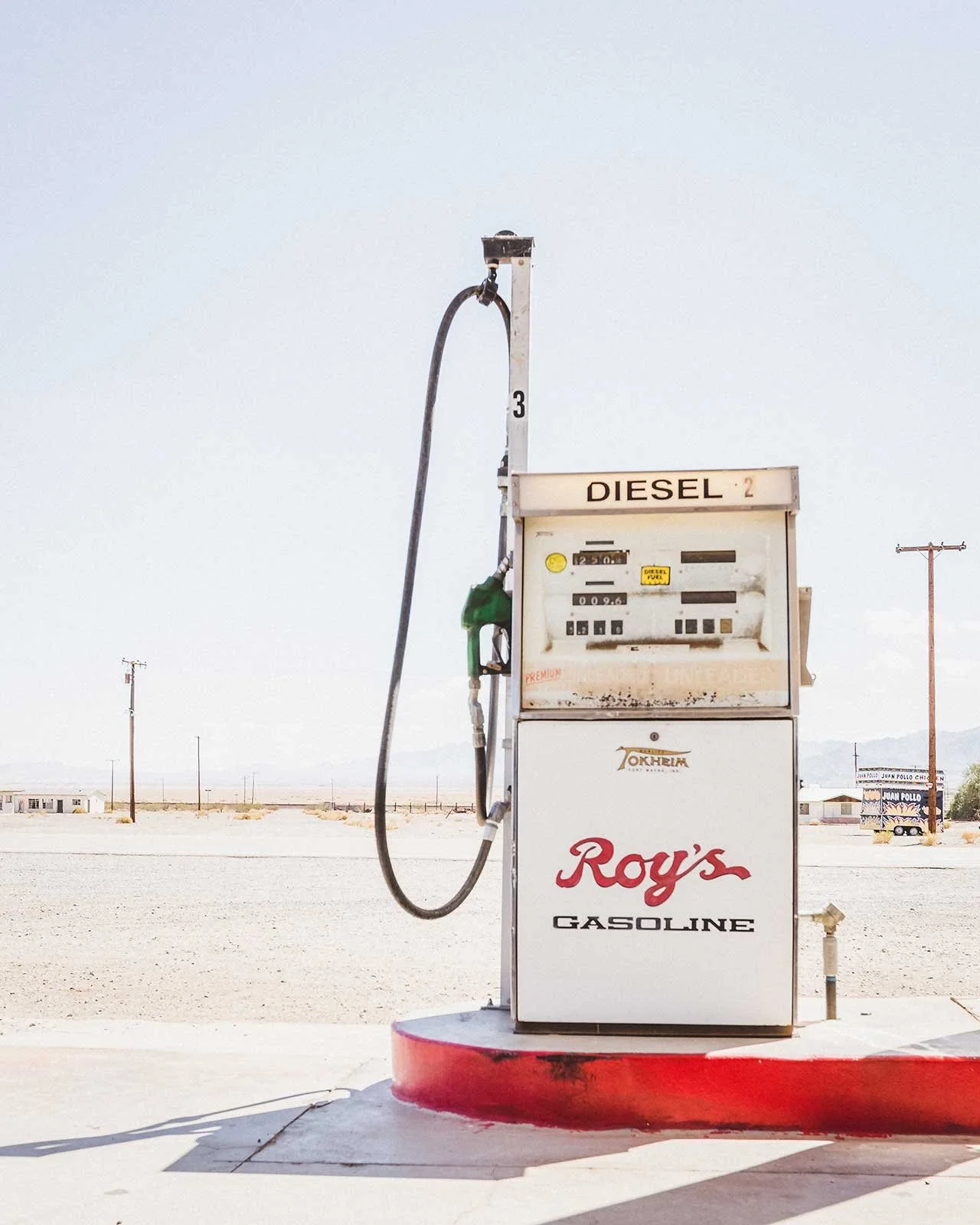 An old, vintage gas pump labeled 'Roy's Gasoline' in a deserted, flat landscape.