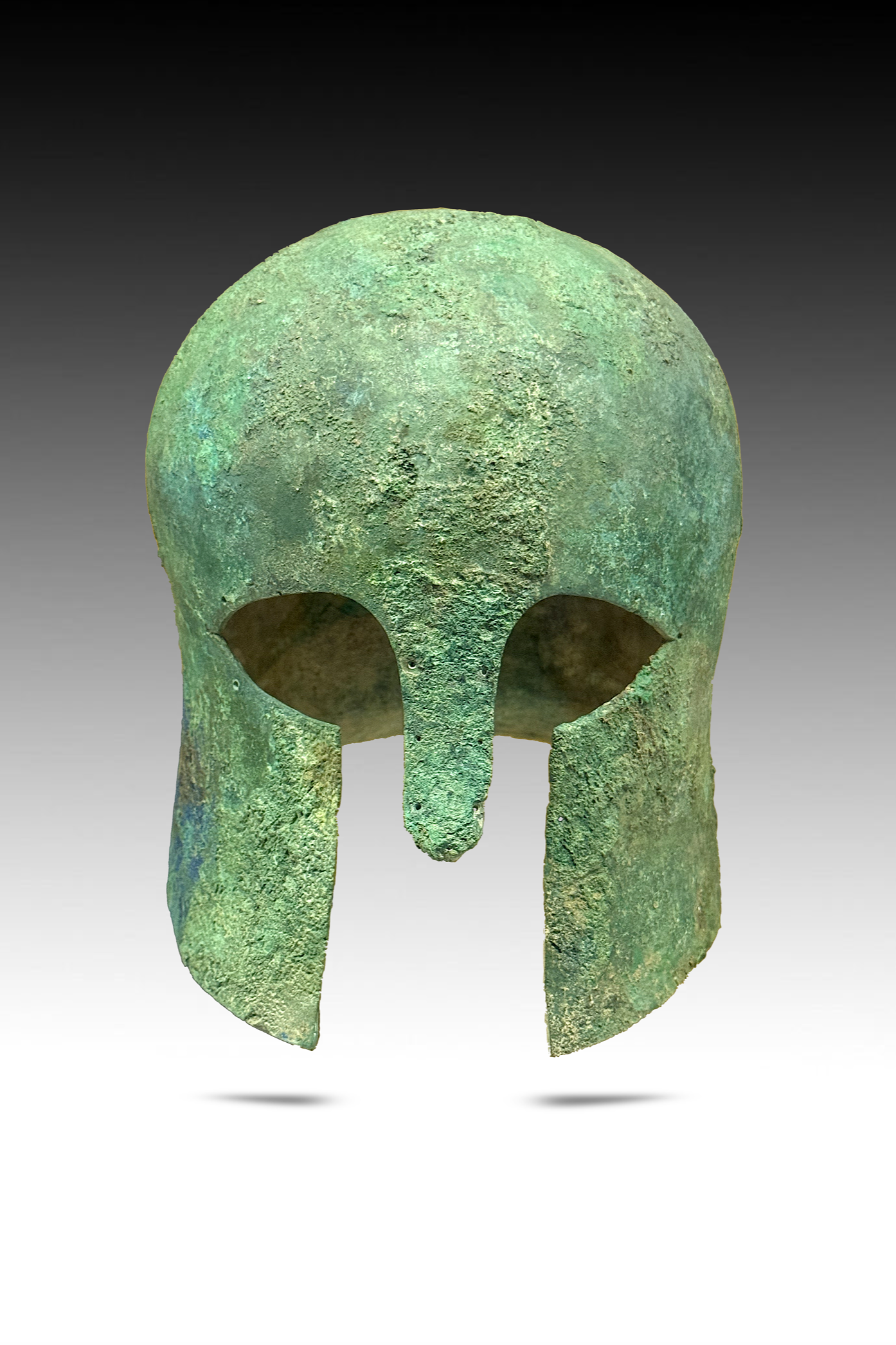 Ancient bronze helmet with green patina and wide open eye holes, missing parts at the bottom.