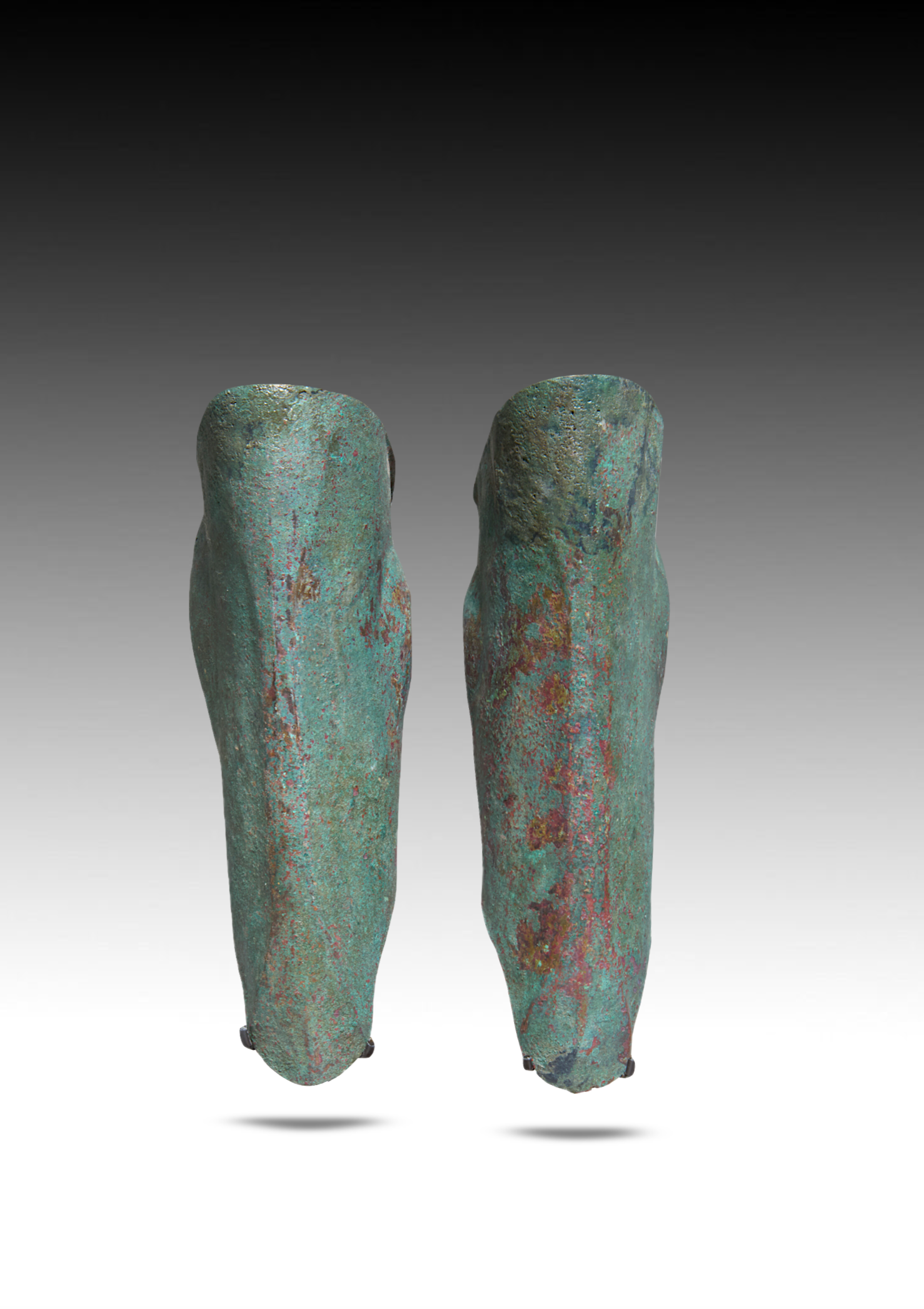 Ancient bronze artificial legs with a patina, standing upright with a plain gradient background.