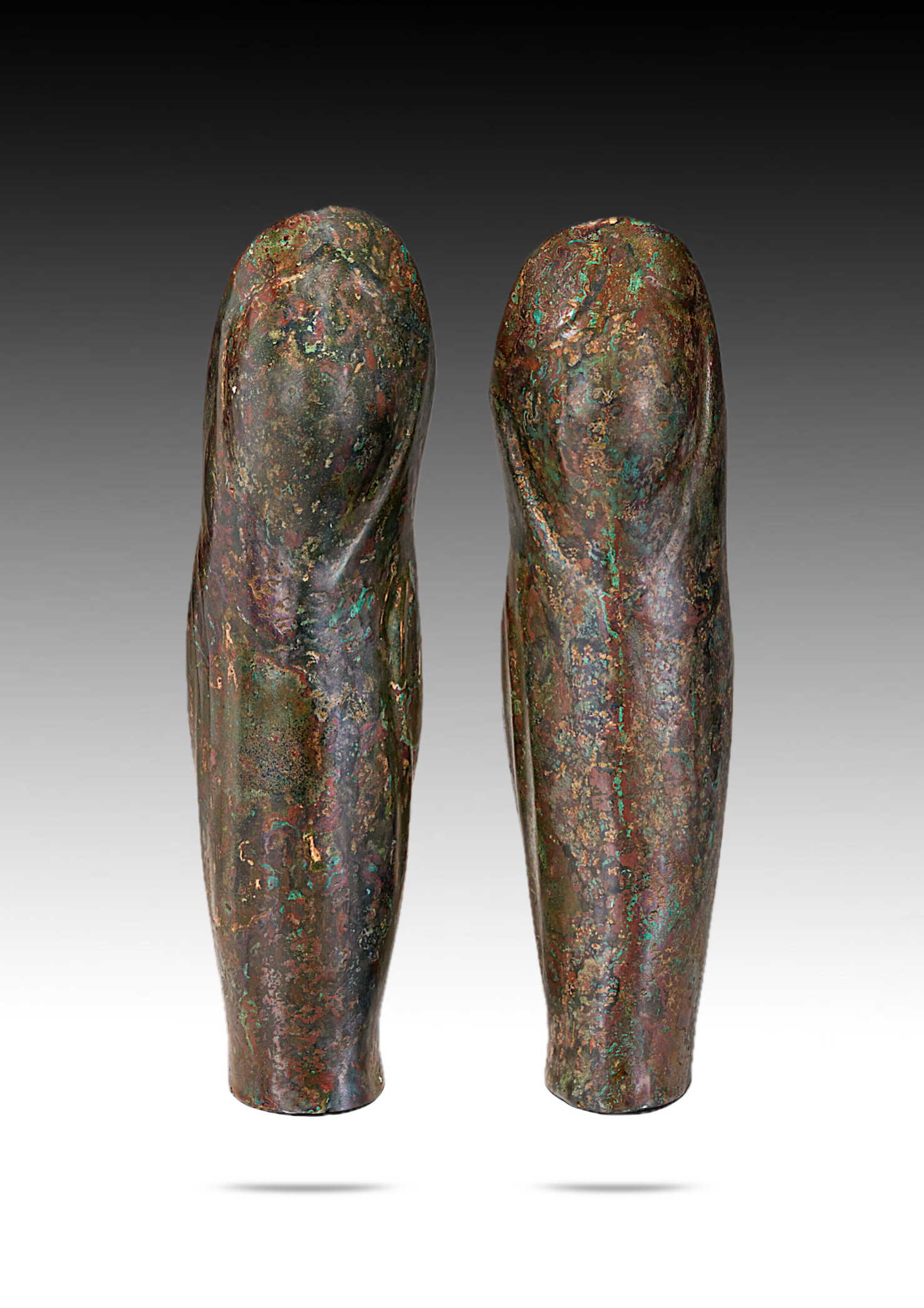 Two abstract metallic sculptures resembling fingers with a colorful patina, positioned side by side against a gray gradient background.