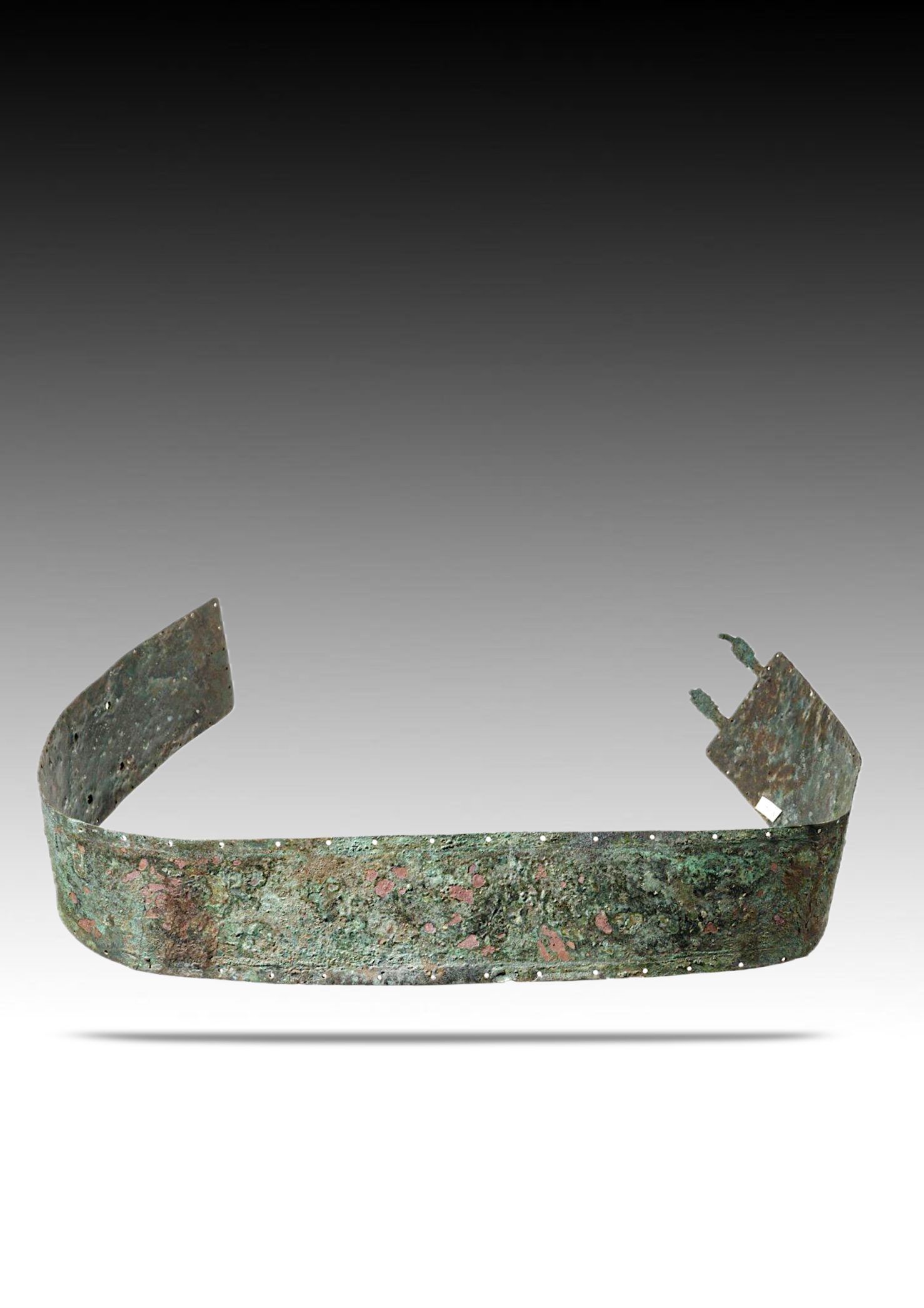 Ancient bronze bracelet with a green patina and decorative pinkish spots.