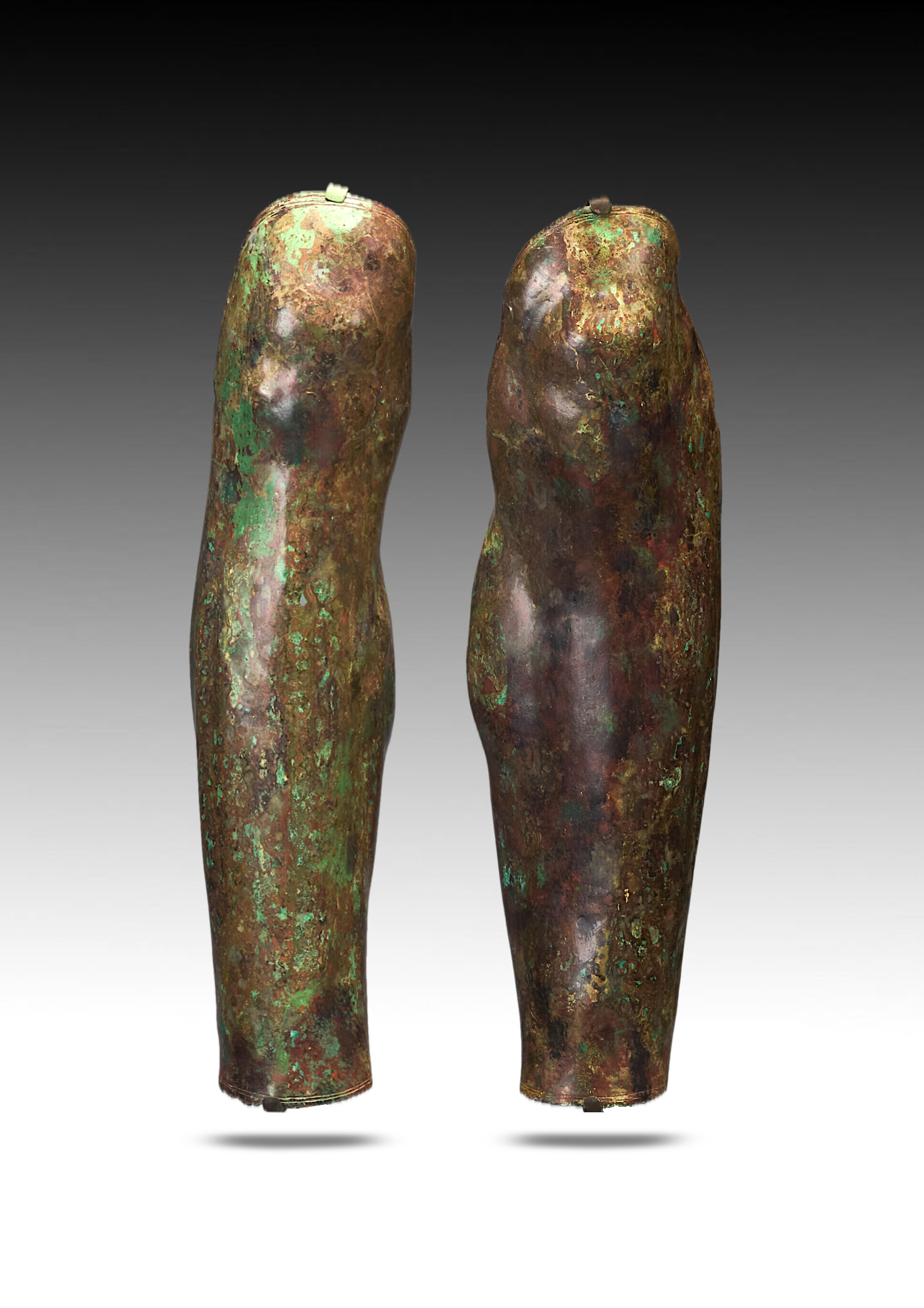 Two ancient bronze statues of legs with a greenish patina, showing signs of corrosion and aging.