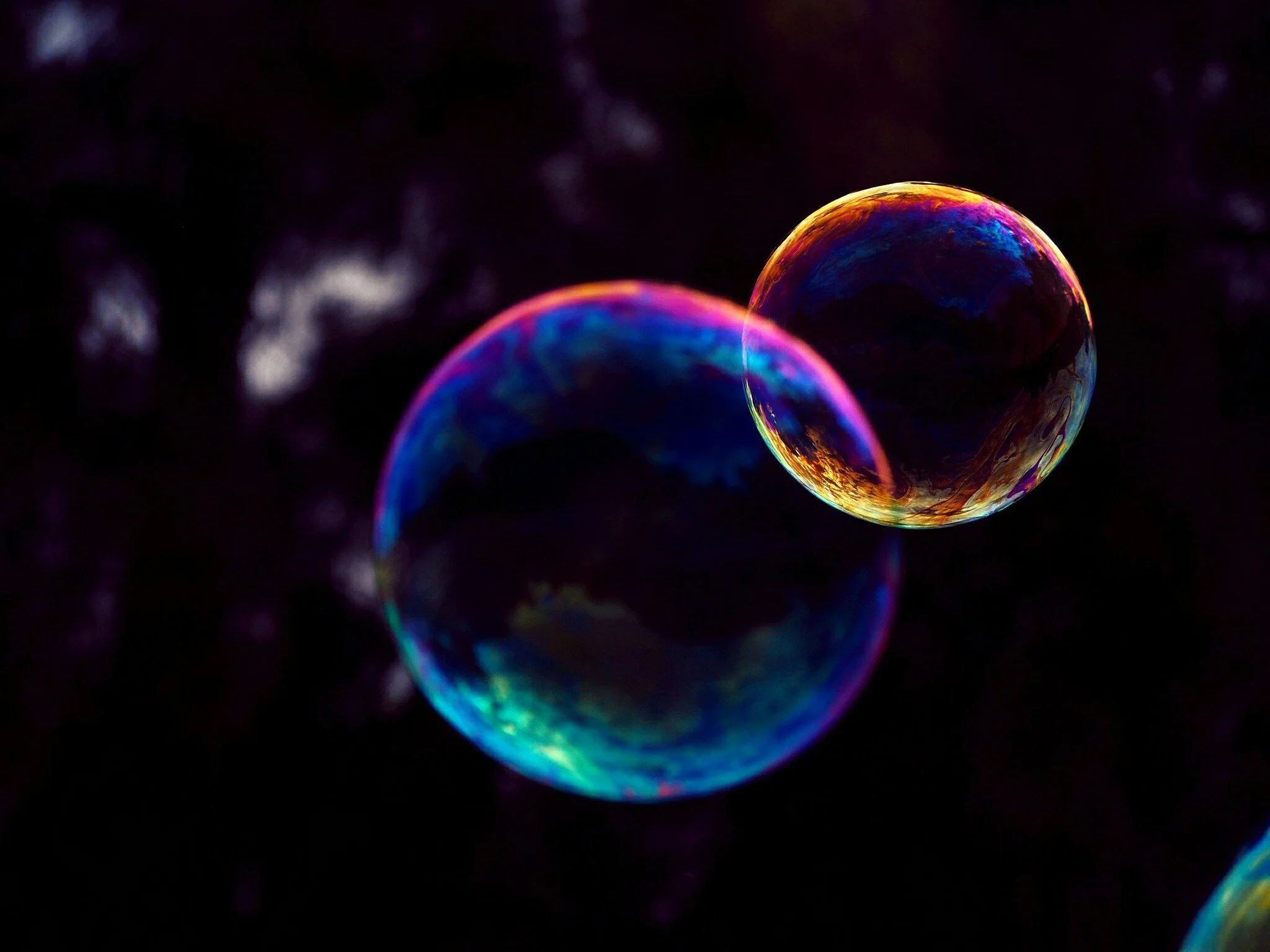 Colorful soap bubbles against a dark background, reflecting vibrant colors.