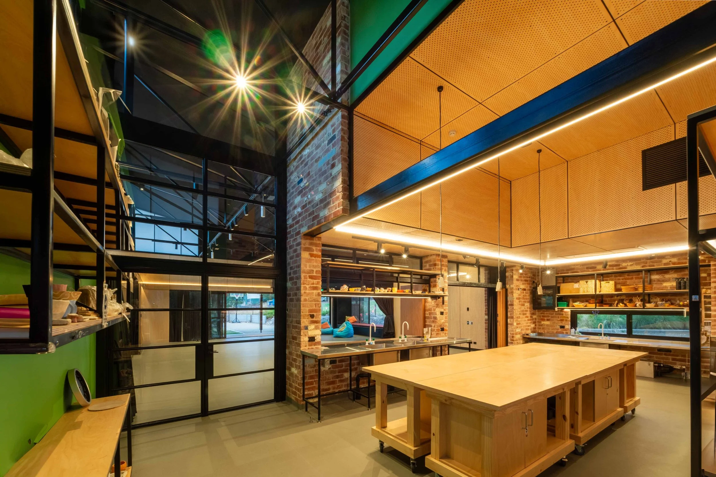 Contemporary interior featuring exposed brick columns, timber ceiling, work benches, sinks and modern lighting.