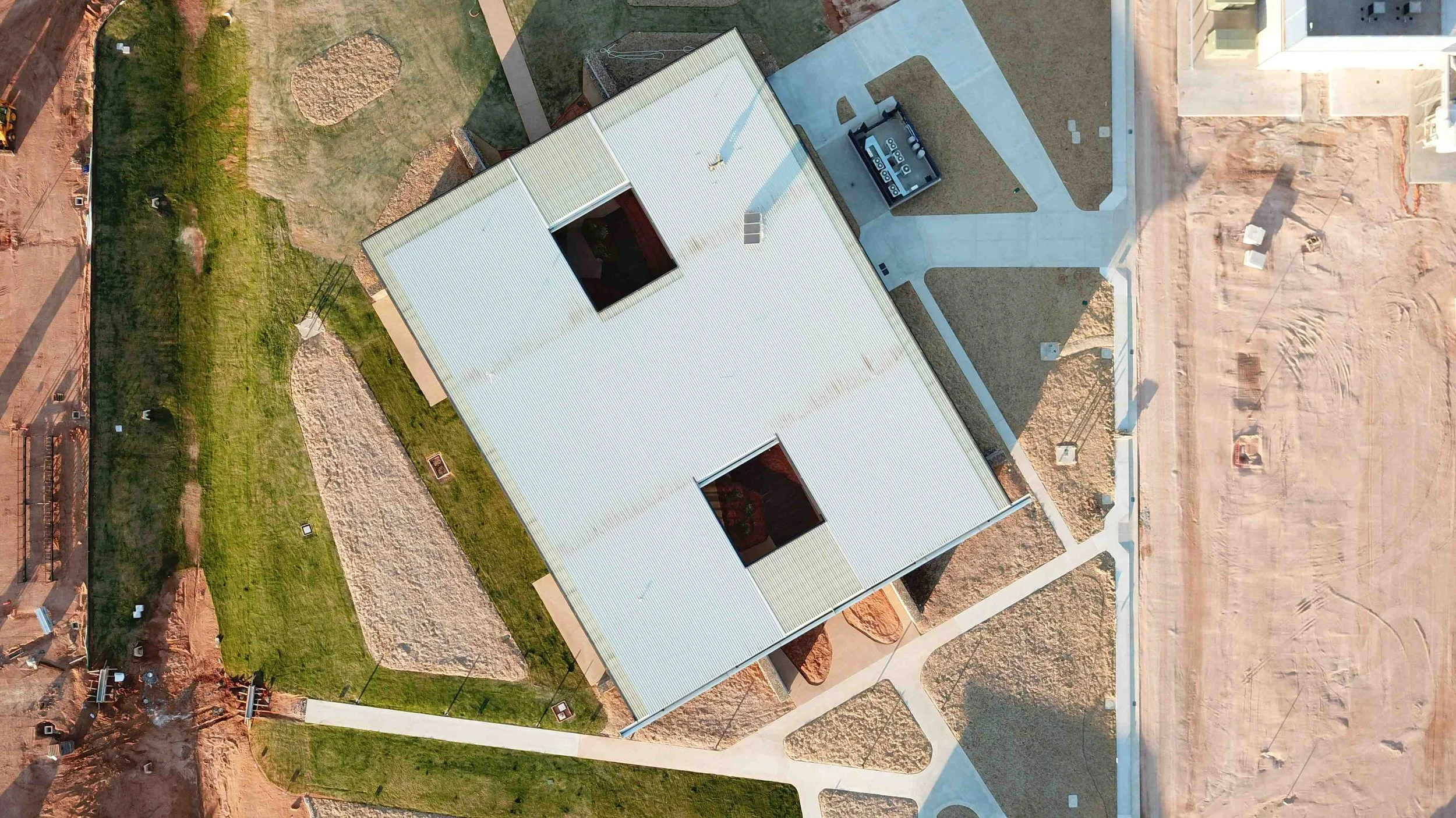 Vertical aerial view of a contemporary commercial building highlighting roof form, landscaped grounds and pedestrian circulation.