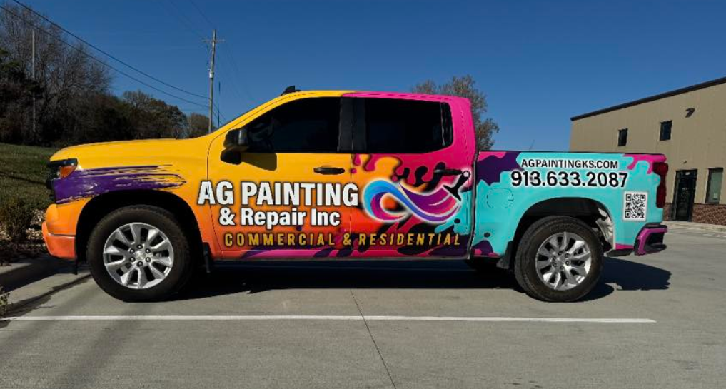 Colored pickup truck advertising AG Painting & Repair Inc with a phone number, website, and QR code, parked in a lot outside a commercial building on a sunny day.
