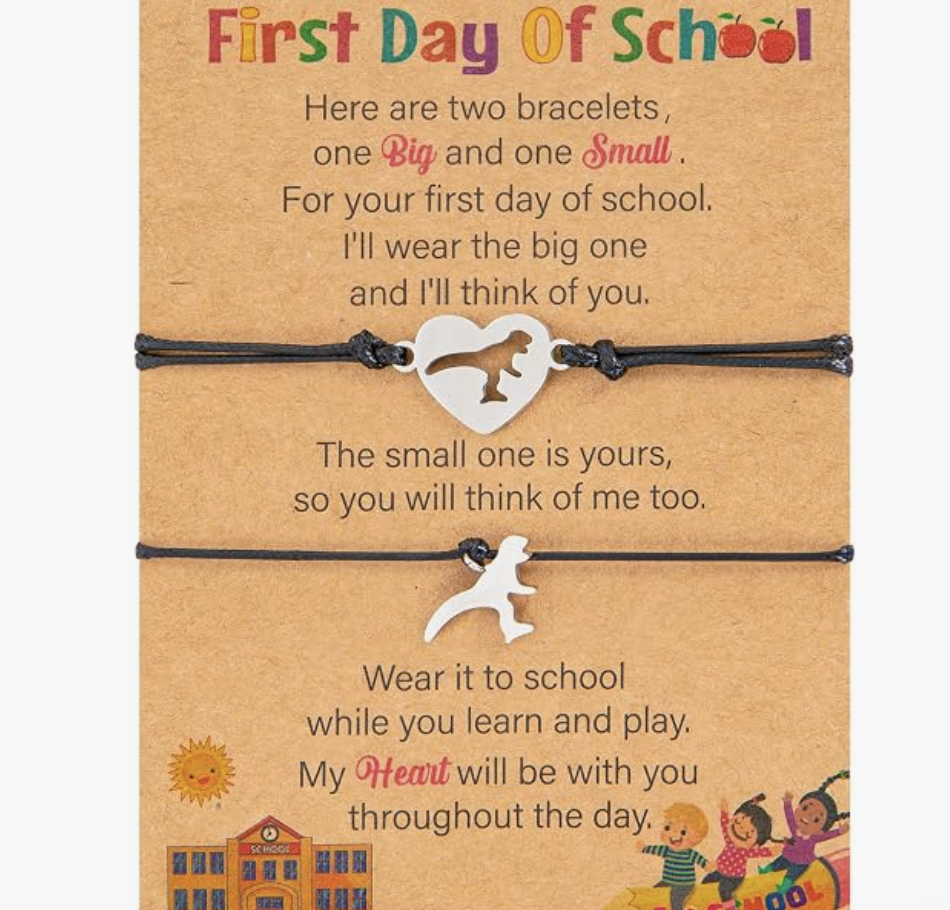 A colorful first day of school card featuring two bracelets, one big and one small. The card has a heartfelt message with a small drawing of a school building and children playing at the bottom.