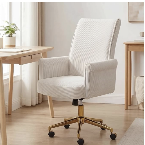 A white office chair with a tall backrest and wooden armrests, on a gold-colored base with wheels, in a room with a wooden desk, a potted plant, and a window with curtains.