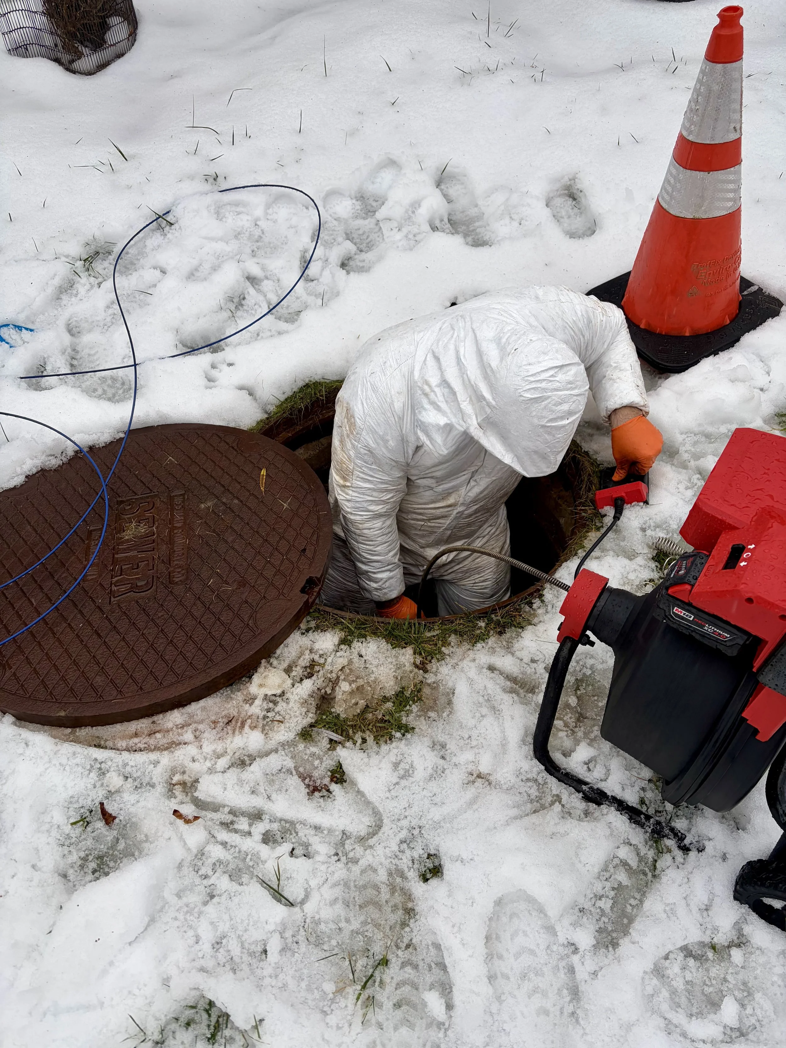 Unclogging a sewer line for a customer using a drain snake.