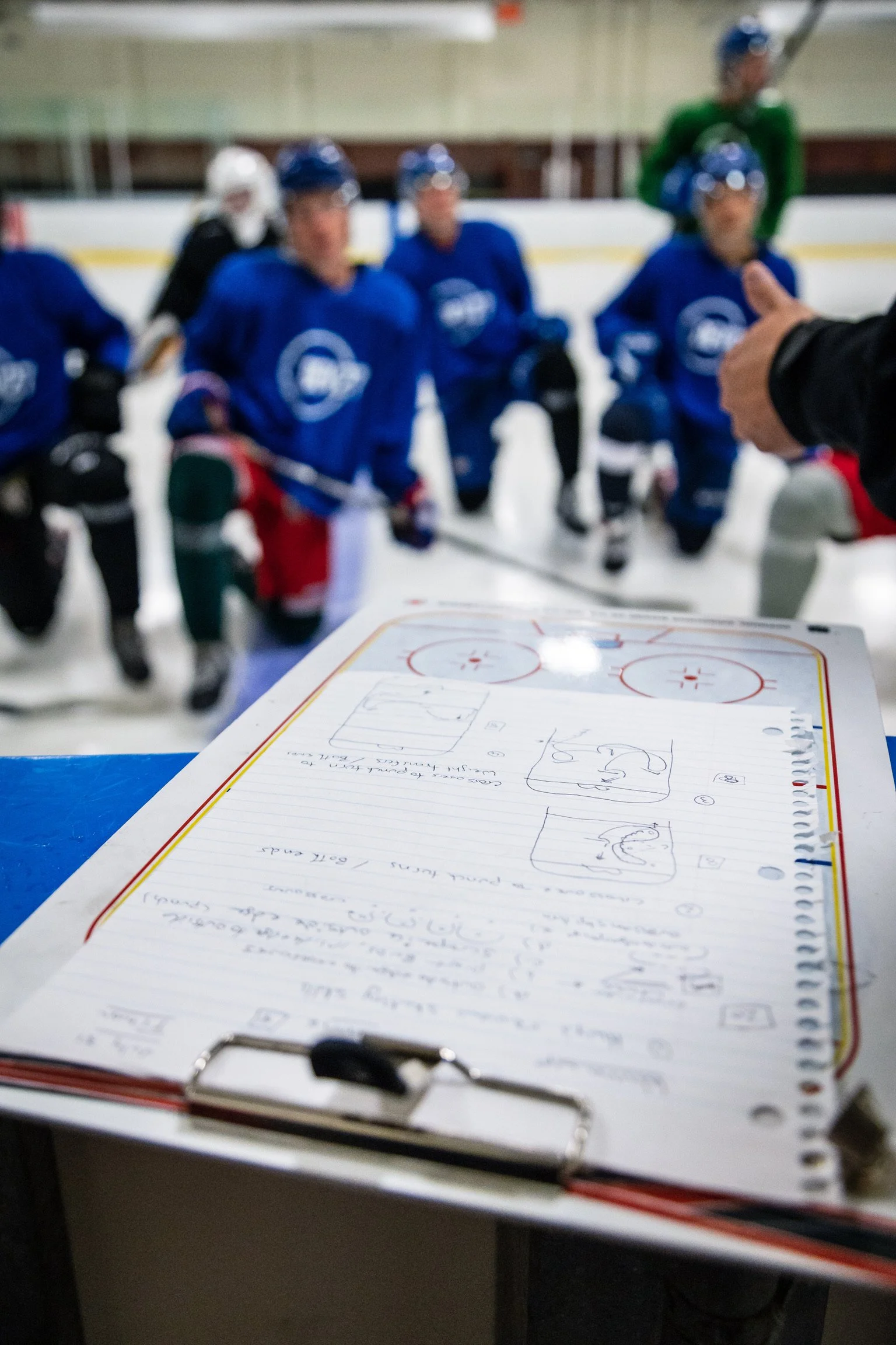 Hockey coach reviewing play diagrams in a strategy notebook during Shift27 athlete development session in Kelowna, BC