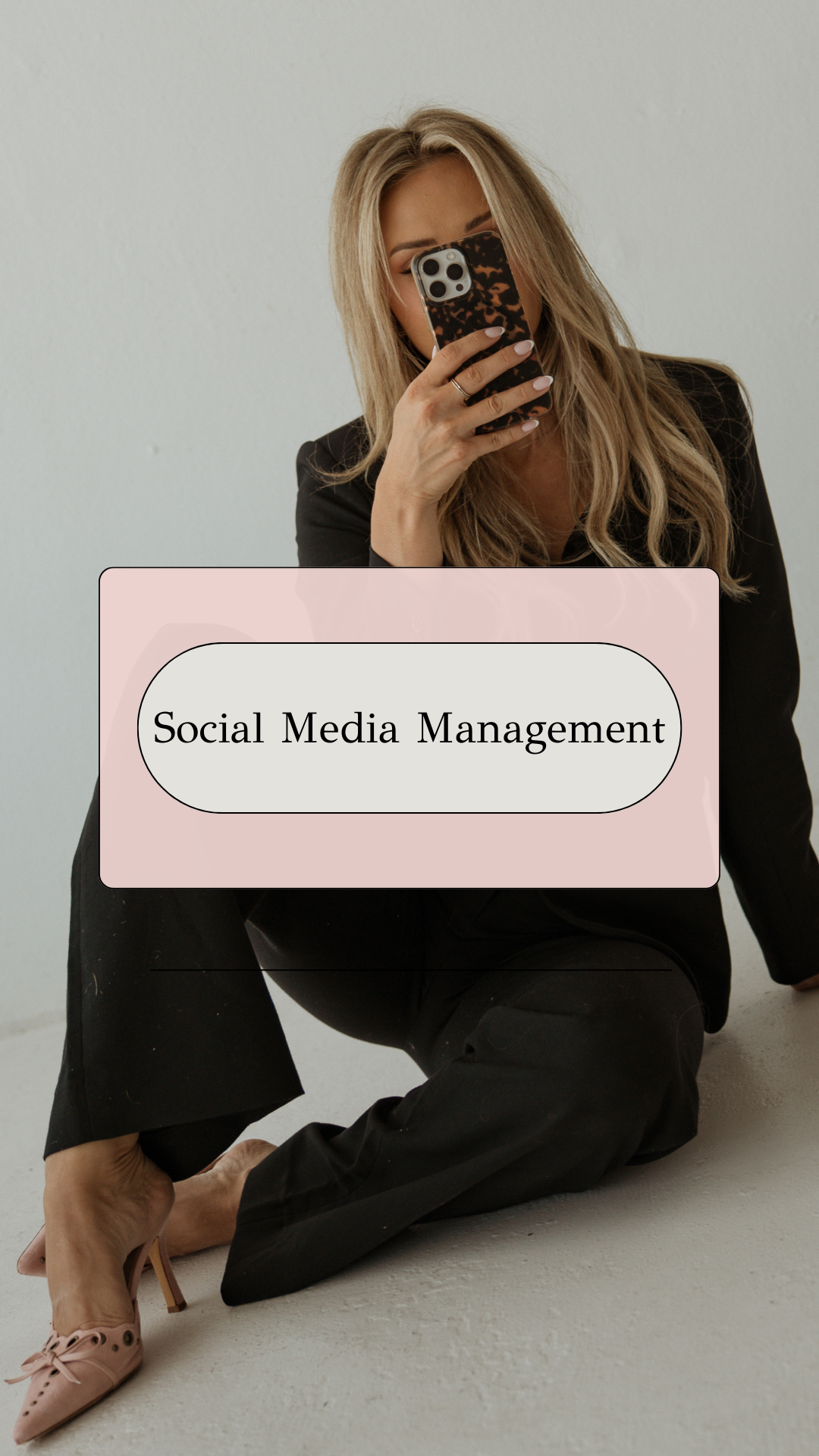 A woman sitting on the floor, holding a smartphone with a tortoiseshell case, taking a selfie. She has long blonde hair and is wearing a black blazer, black pants, and pink high heels. There is a text box over her with the words 'Social Media Management'.
